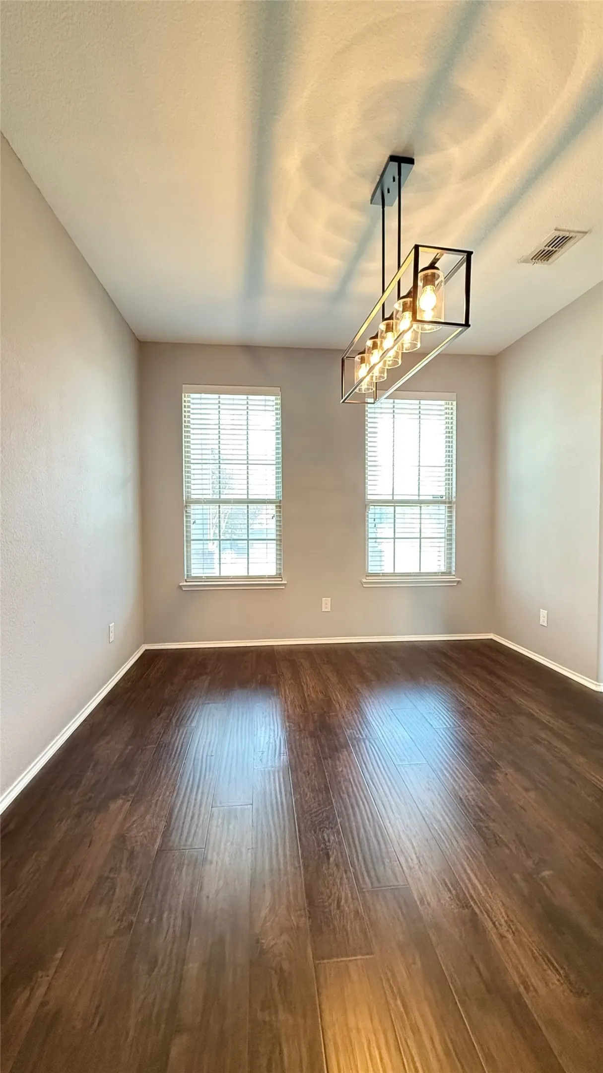 Unfurnished room featuring healthy amount of natural light, dark wood-style floors, and baseboards
