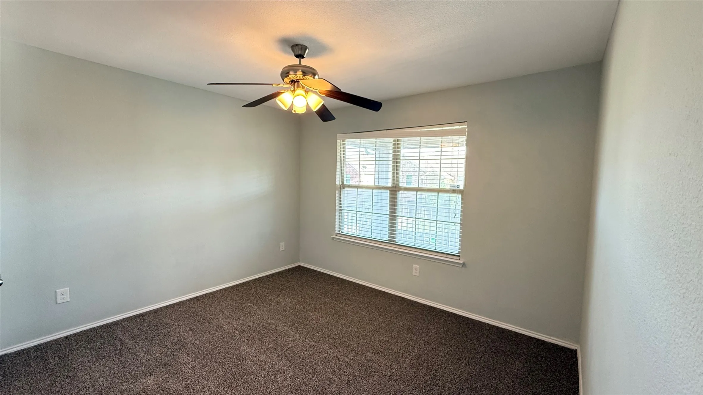 Spare room with dark colored carpet, a ceiling fan, and baseboards