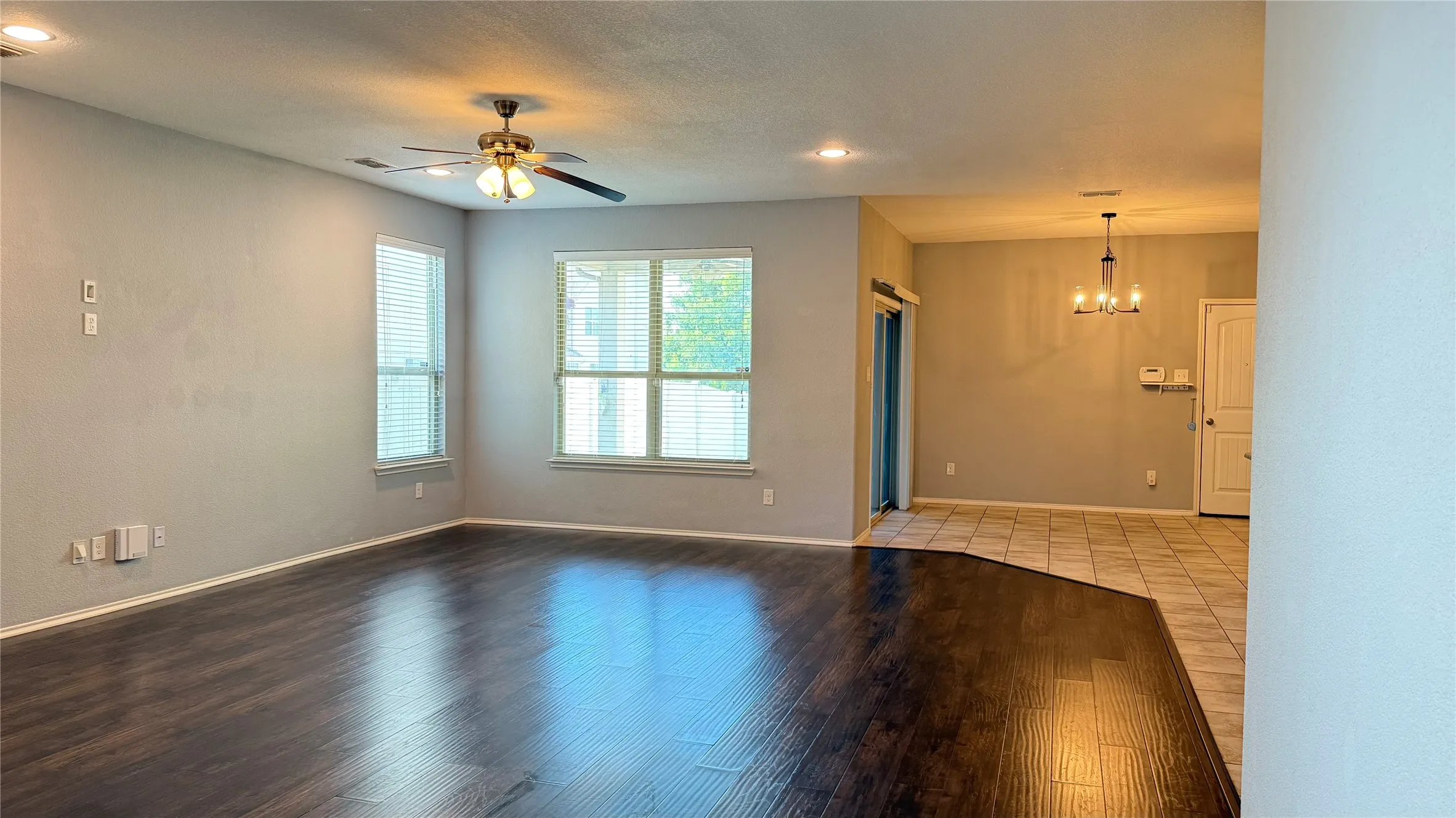 Unfurnished room featuring a chandelier, ceiling fan, wood finished floors, baseboards, and recessed lighting