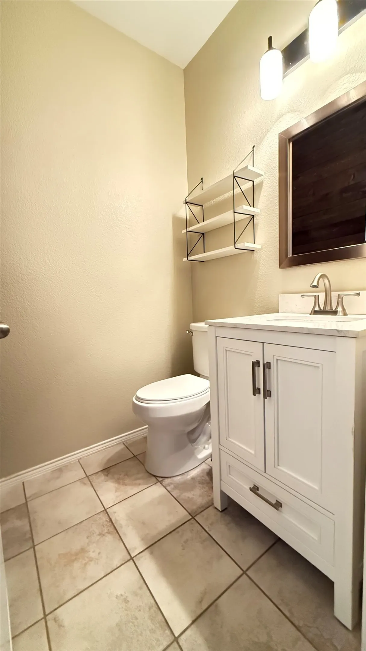 Bathroom with toilet, vanity, baseboards, and tile patterned floors