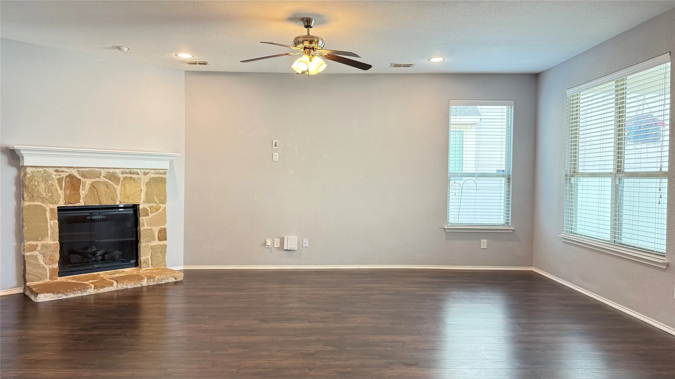 Unfurnished living room featuring dark wood-style floors, ceiling fan, baseboards, a fireplace, and recessed lighting