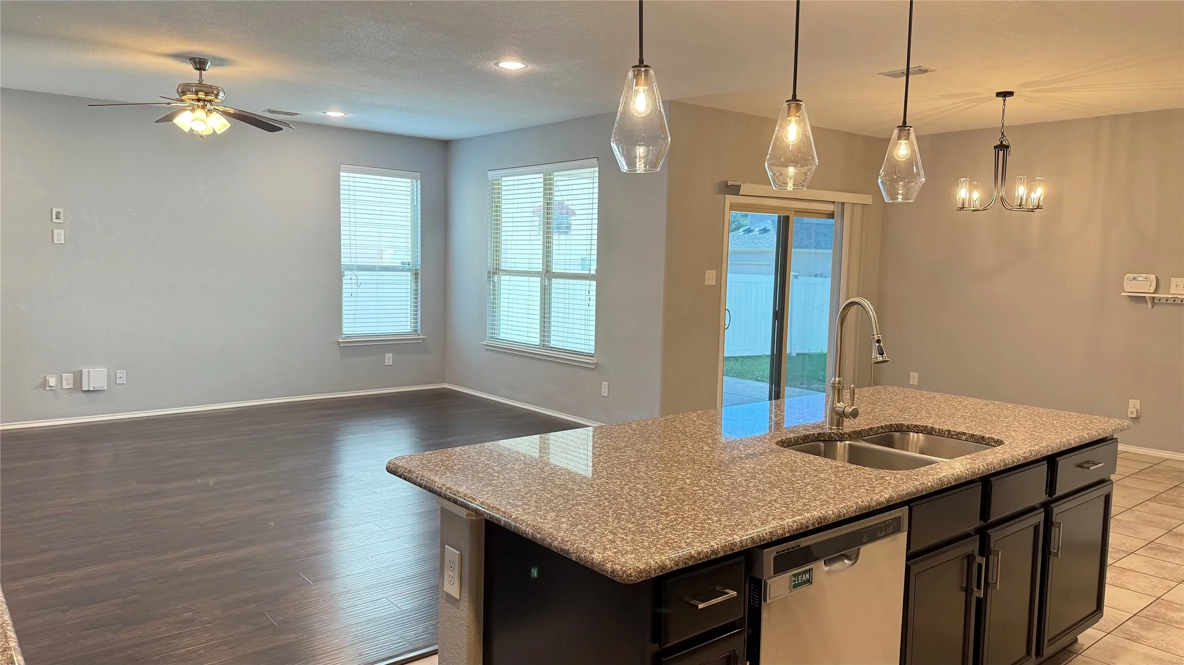 Kitchen featuring stainless steel dishwasher, a sink, open floor plan, baseboards, and an island with sink