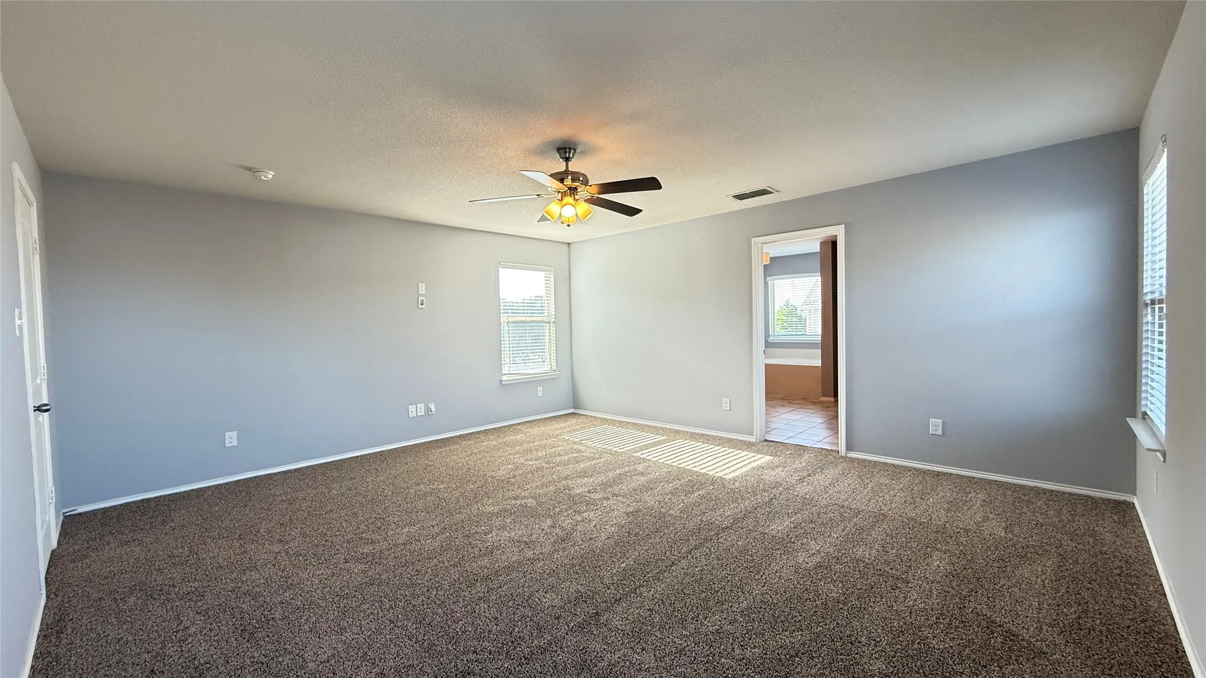 Carpeted empty room with a ceiling fan, baseboards, and a smoke detector
