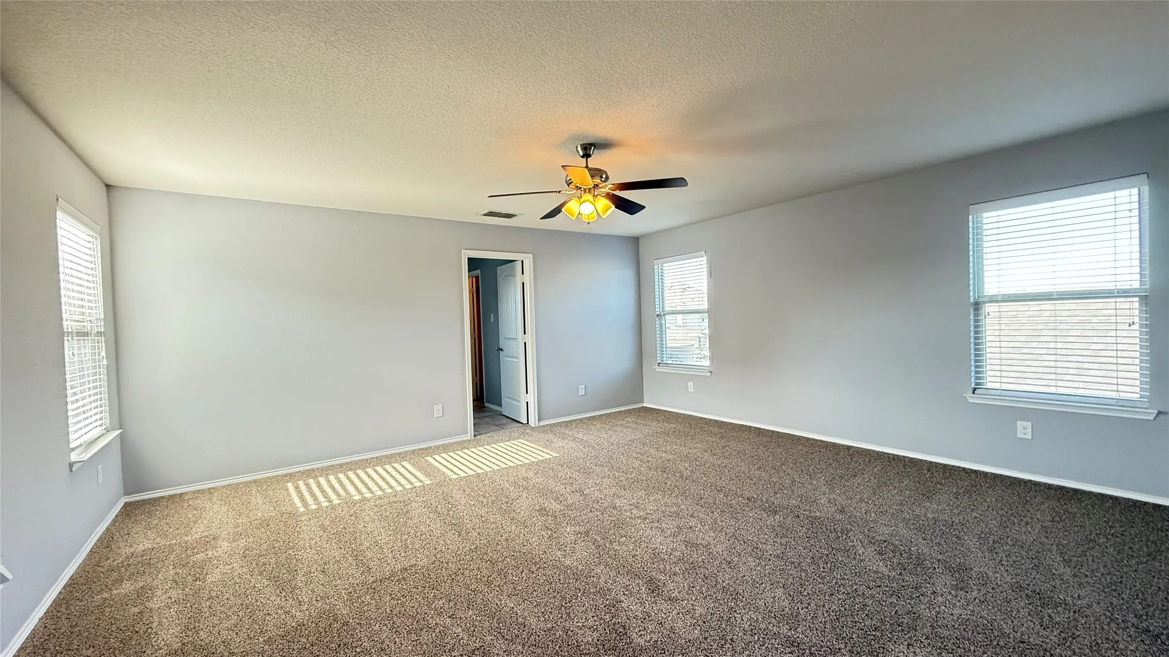 Carpeted empty room featuring ceiling fan, baseboards, and a textured ceiling