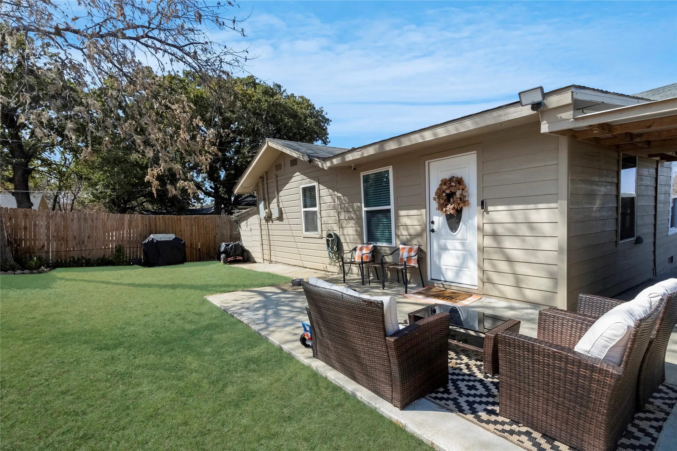 Expansive backyard featuring a concrete patio, manicured lawn, and privacy fencing