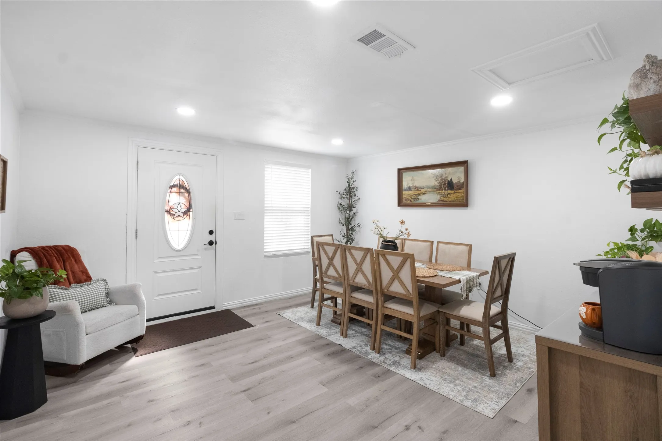White entry door with an oval glass insert, wood-finish flooring, recessed lighting, and a window with blinds