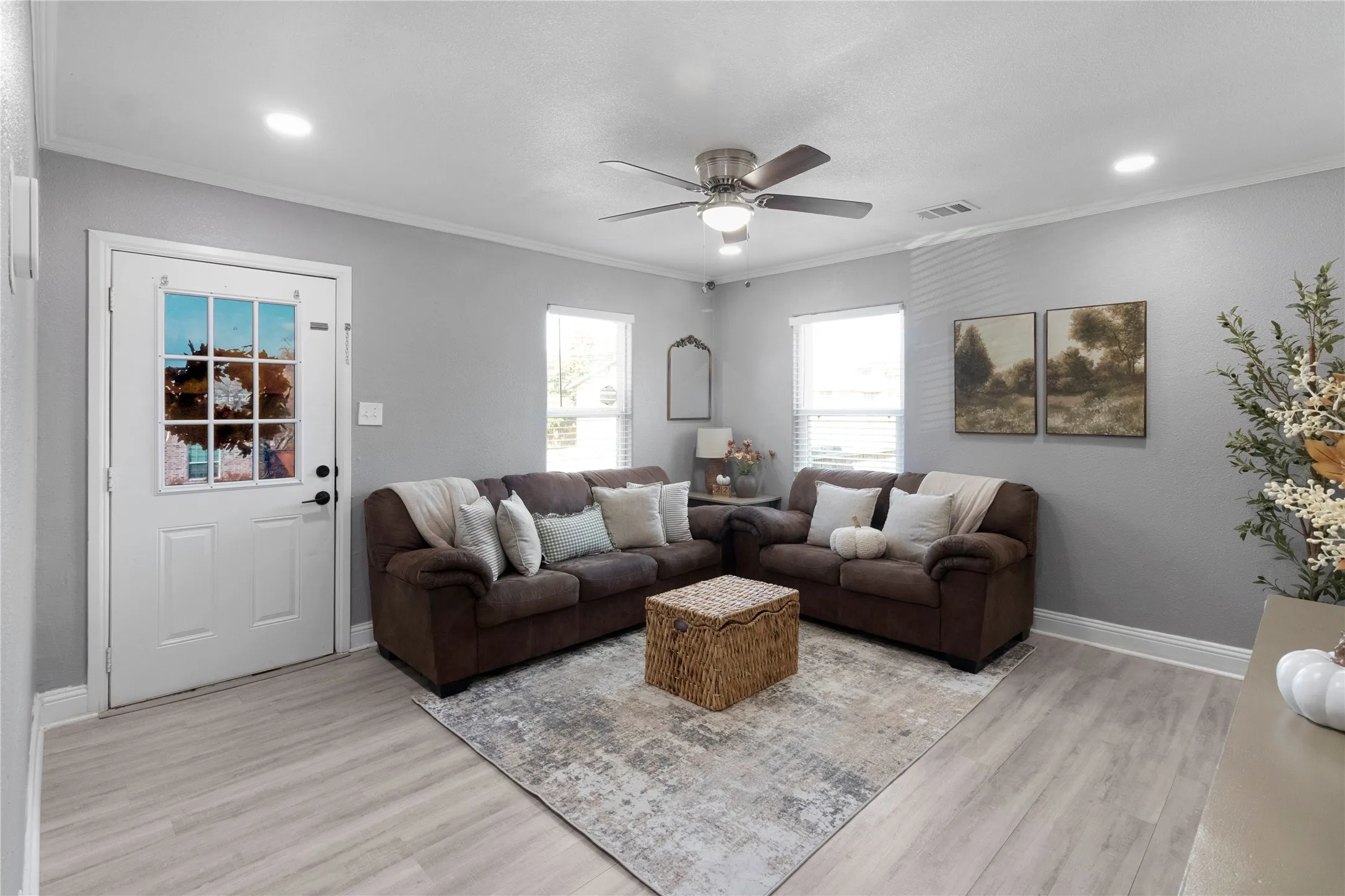 Recessed lighting, ceiling fan with integrated light, multiple windows, light-toned wood-finish flooring, and crown molding