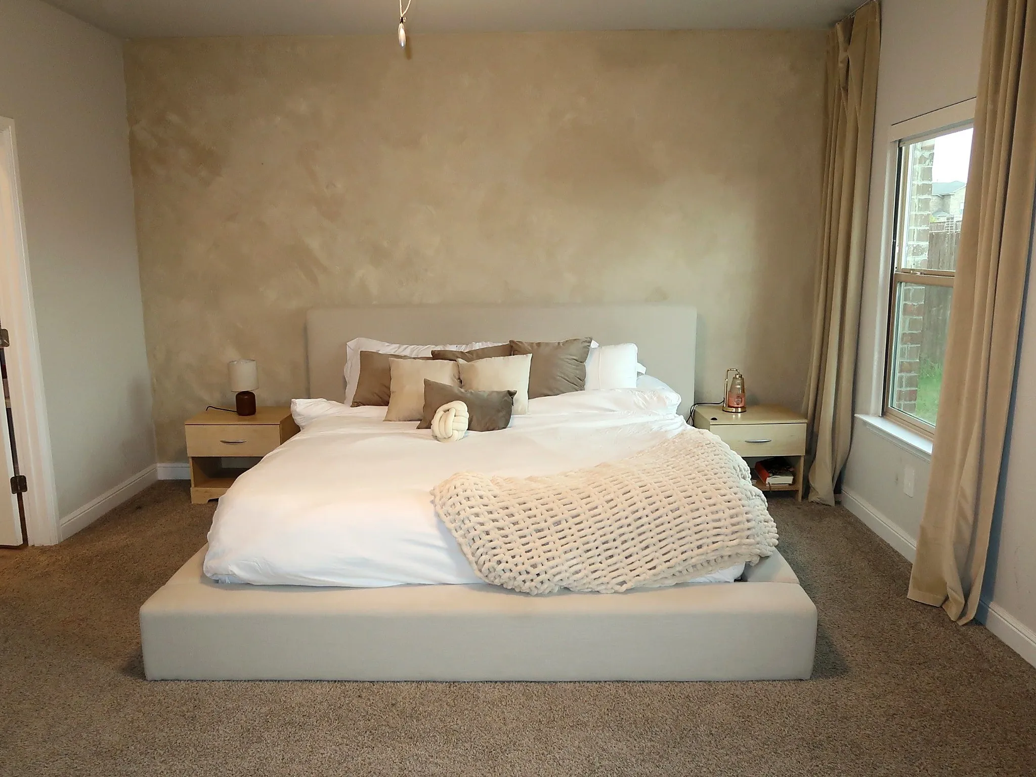 Neutral toned walls with textured finish, carpeted flooring, and a double-hung window