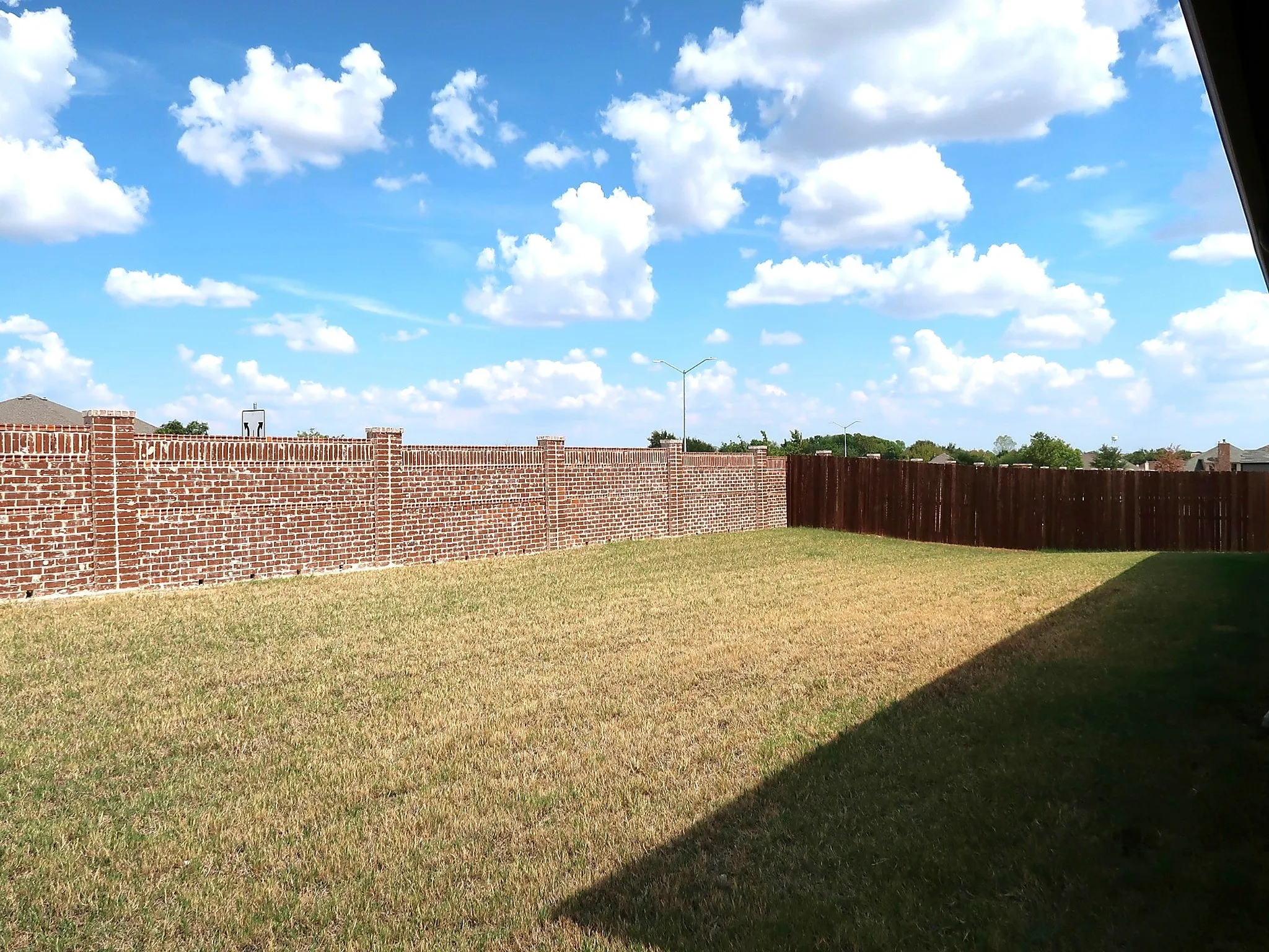 Expansive outdoor space featuring a brick privacy fence and a dark wood privacy fence