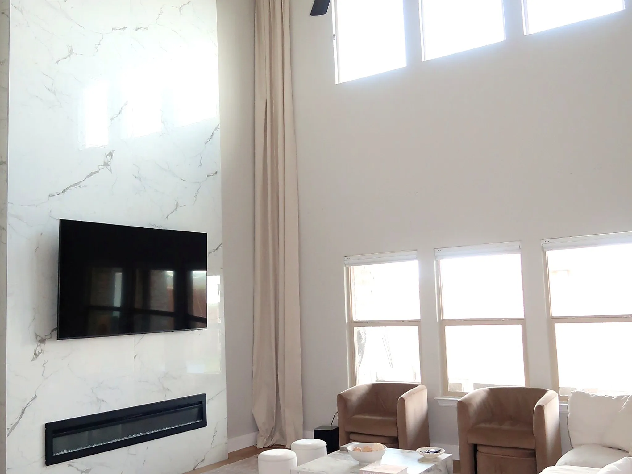 Two-story living area featuring a full-height fireplace with a linear insert and a marble-finish surround