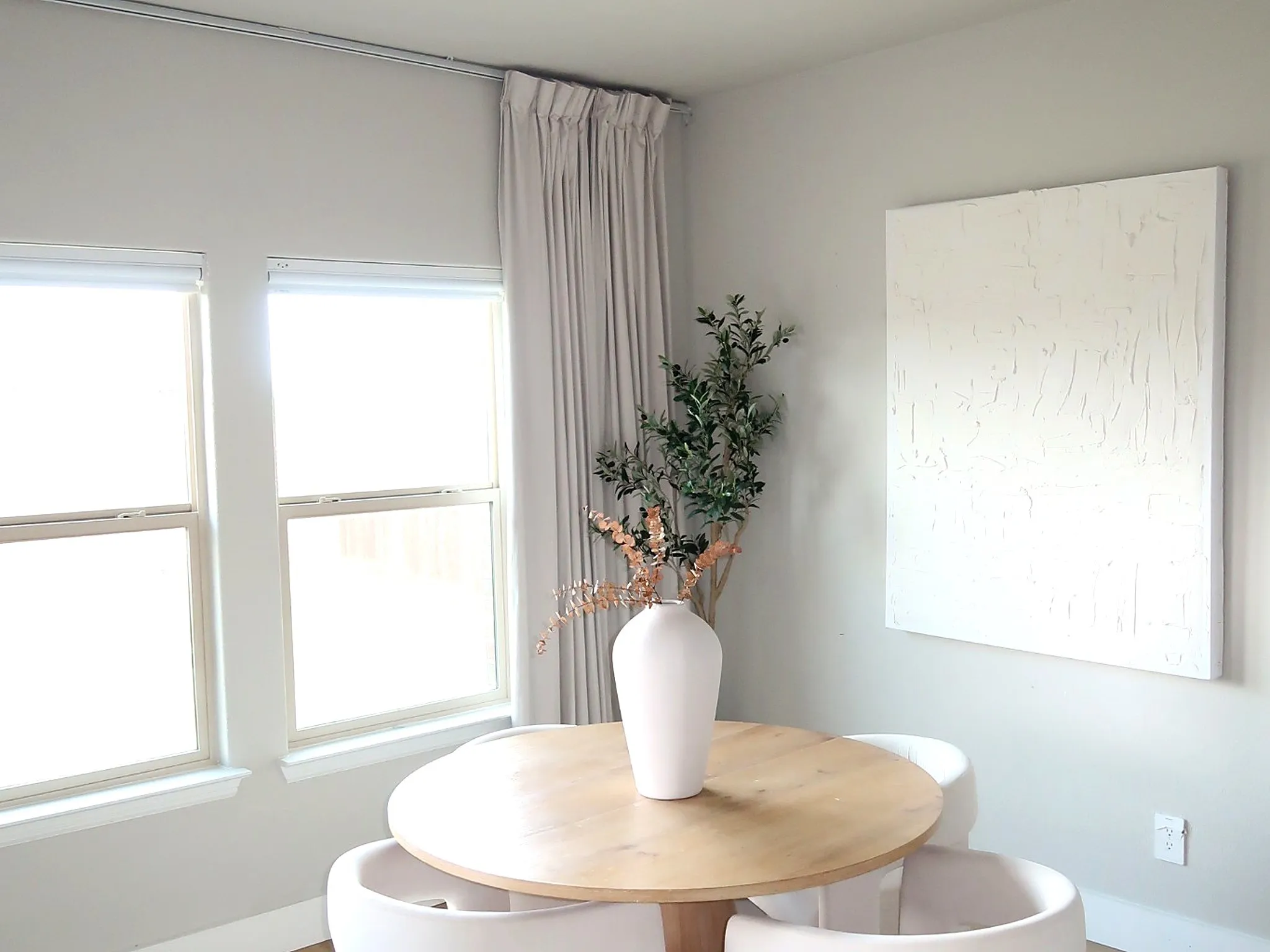 Dual windows with roller shades, light-toned walls, and wood-finish flooring