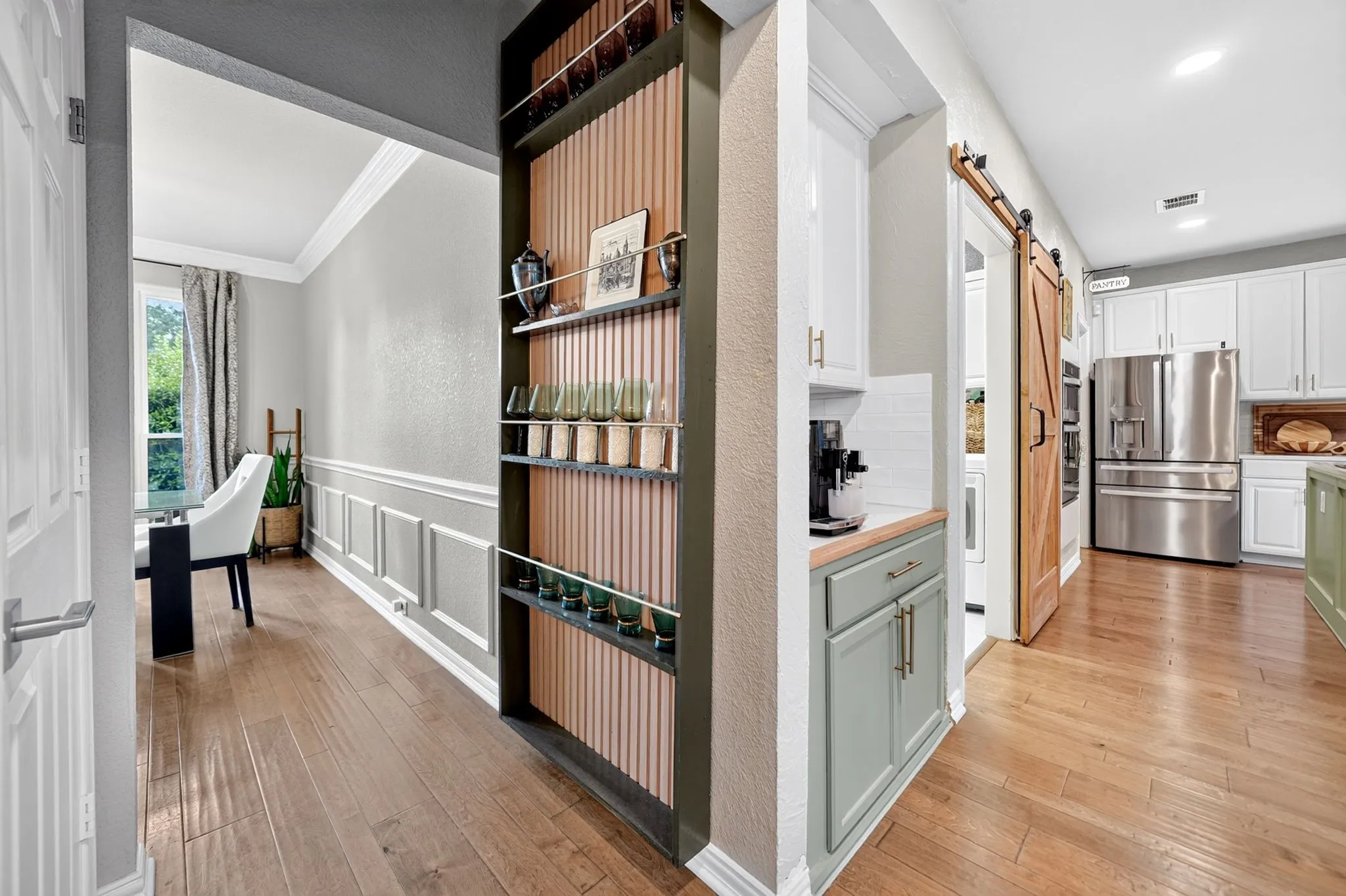Wood-finish flooring throughout, custom built-in shelving, wainscoting, and a sliding barn door