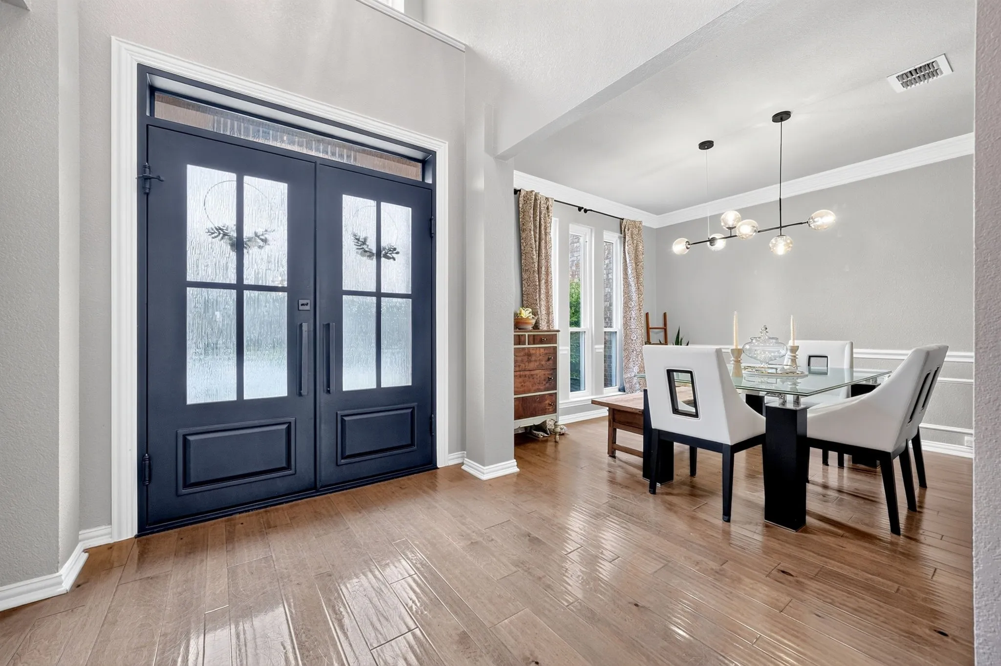 Double-door entry with transom window, wood-finish flooring, and crown molding
