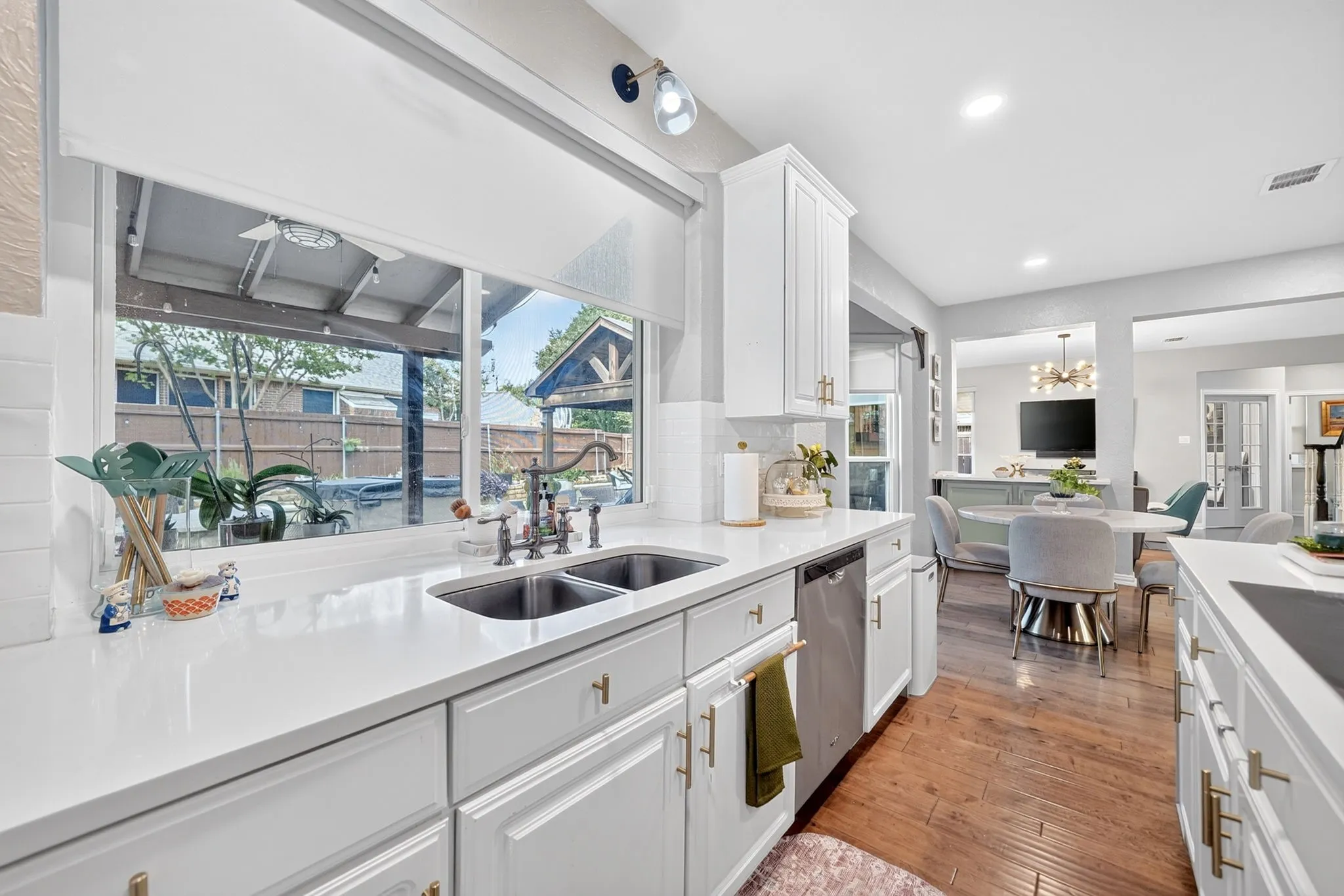 White cabinetry, stainless steel dishwasher, wood-finish flooring, recessed lighting, and a dual basin sink
