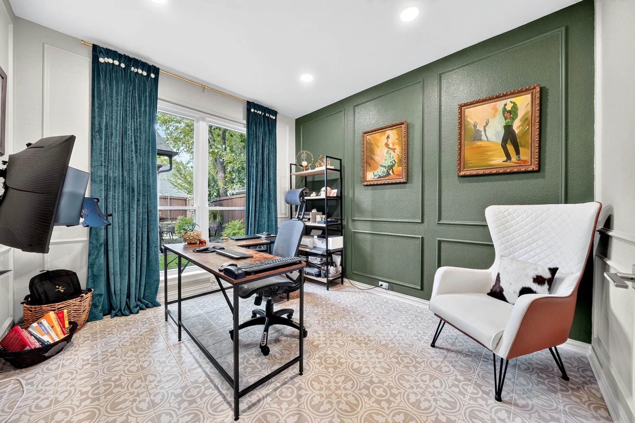 Patterned tile flooring, a dark green accent wall with decorative molding, large windows with full-length drapery, recessed lighting, and a built-in wall-mounted television bracket