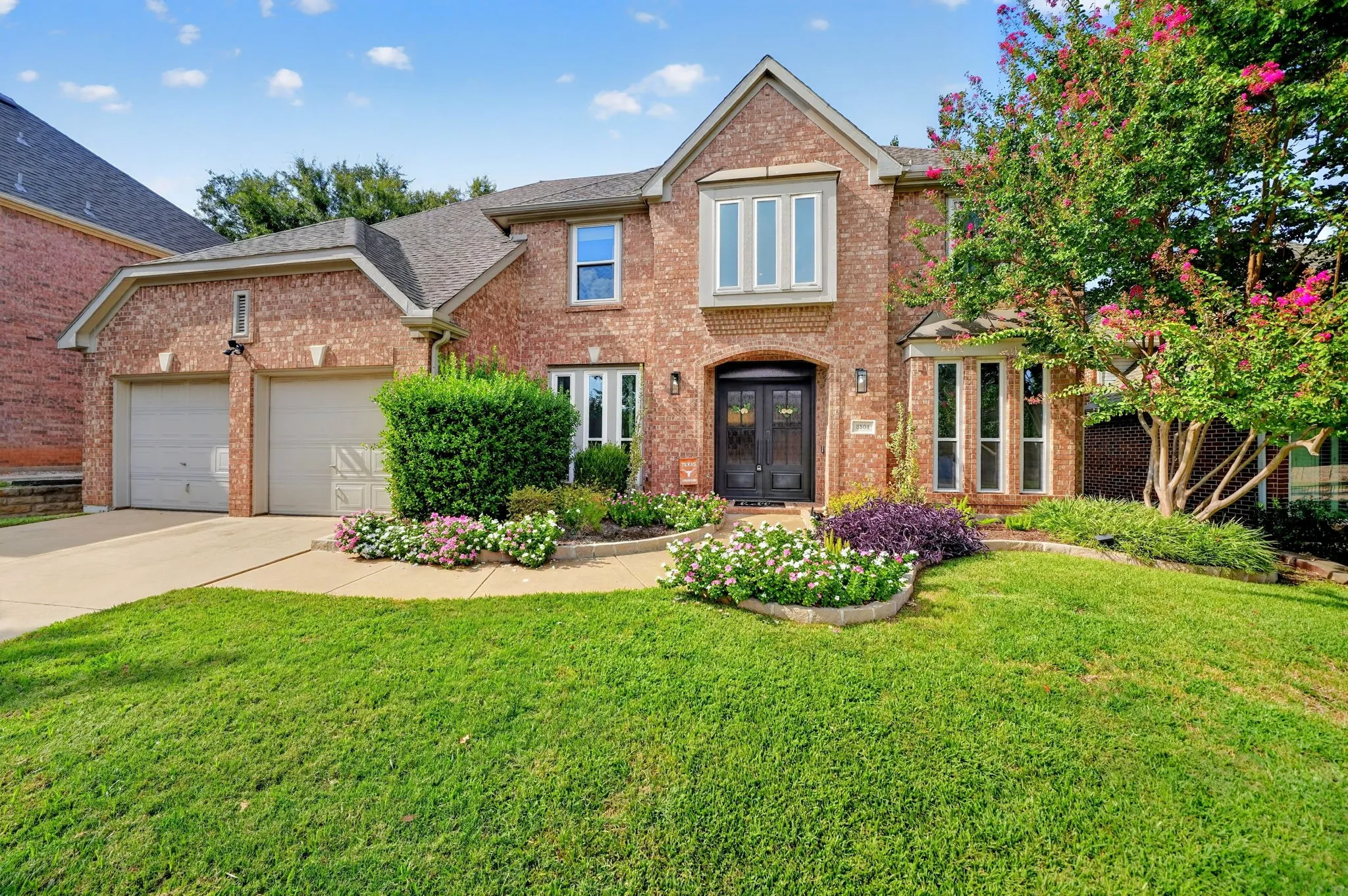 Brick exterior with a gabled roofline, arched double entry doors, bay windows, and an attached two-car garage