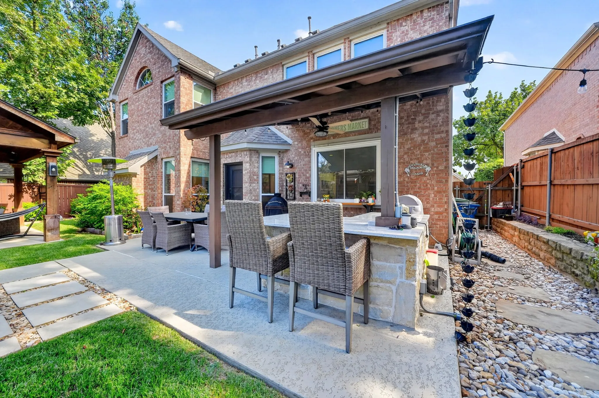 Paved patio featuring an outdoor kitchen with stone veneer and a pergola