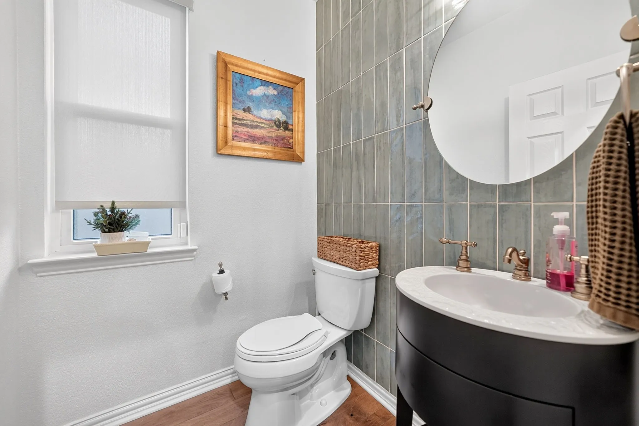 Modern vanity with an integrated basin, brass fixtures, and a circular wall mirror