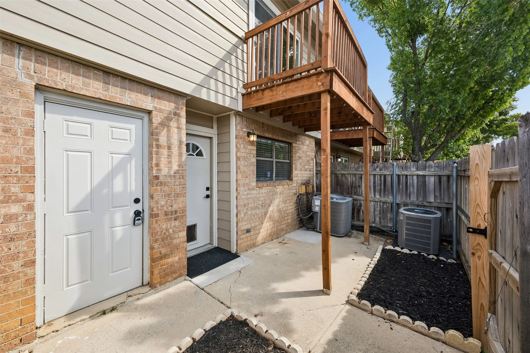 Brick exterior with wood siding, private wooden deck, concrete patio, and fenced yard