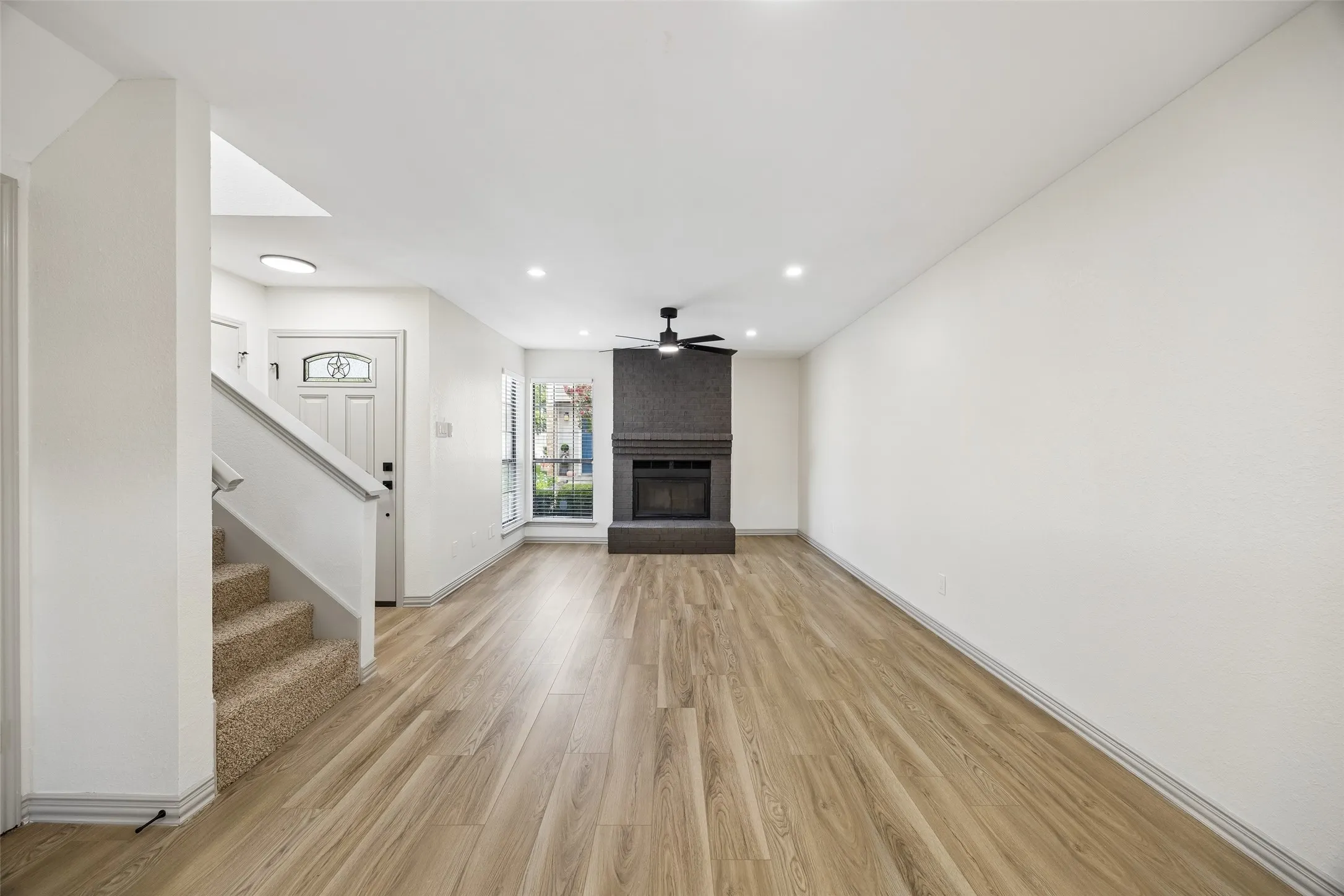 Fireplace with dark stone surround, wood-finish flooring, recessed lighting, and a ceiling fan