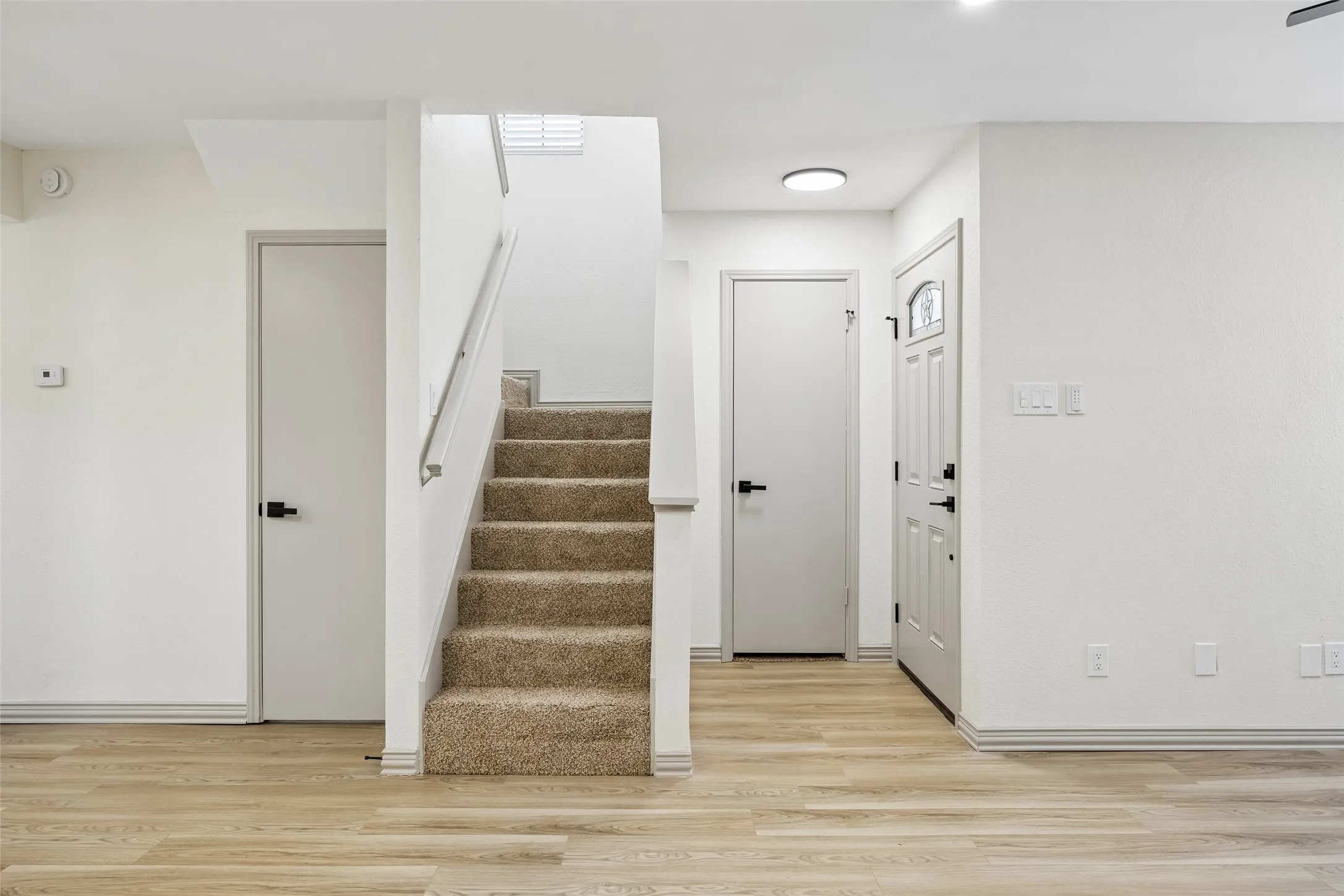 Wood-finish flooring, carpeted staircase with handrail, and contemporary interior doors