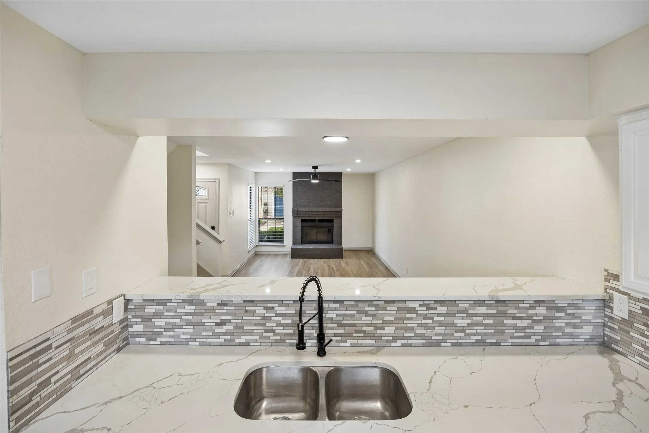 Kitchen pass-through with a dual basin sink, gooseneck faucet, and mosaic tile backsplash