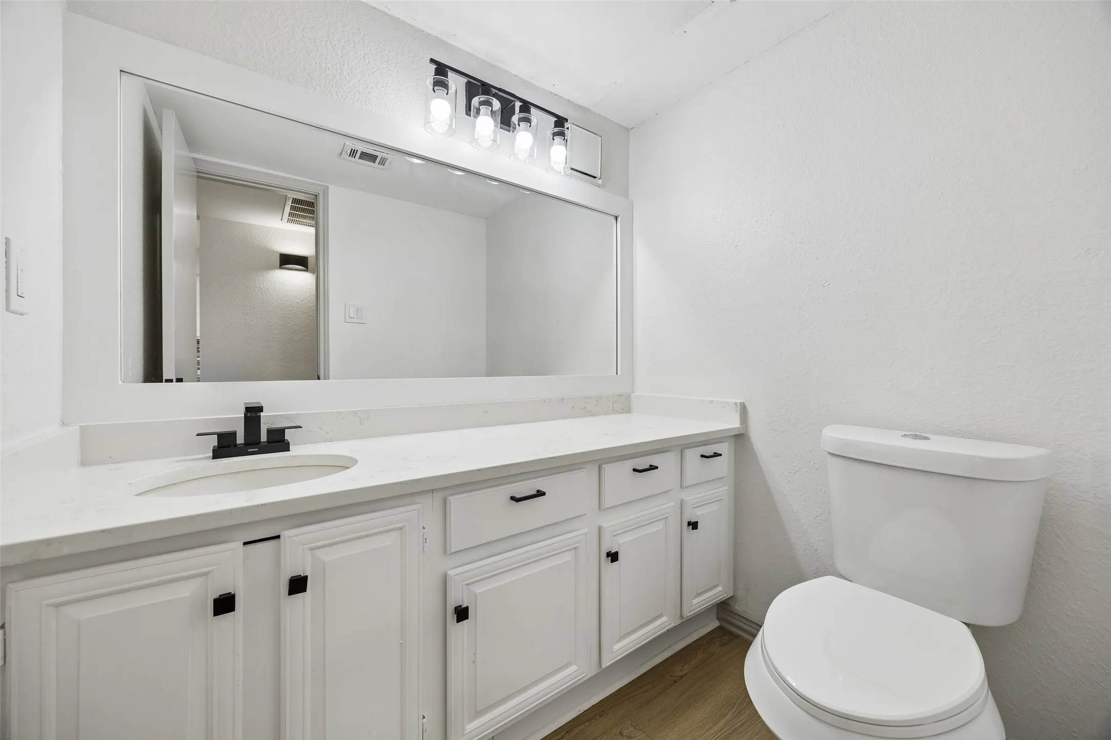 White vanity with black hardware, white countertop, undermount sink, and black faucet