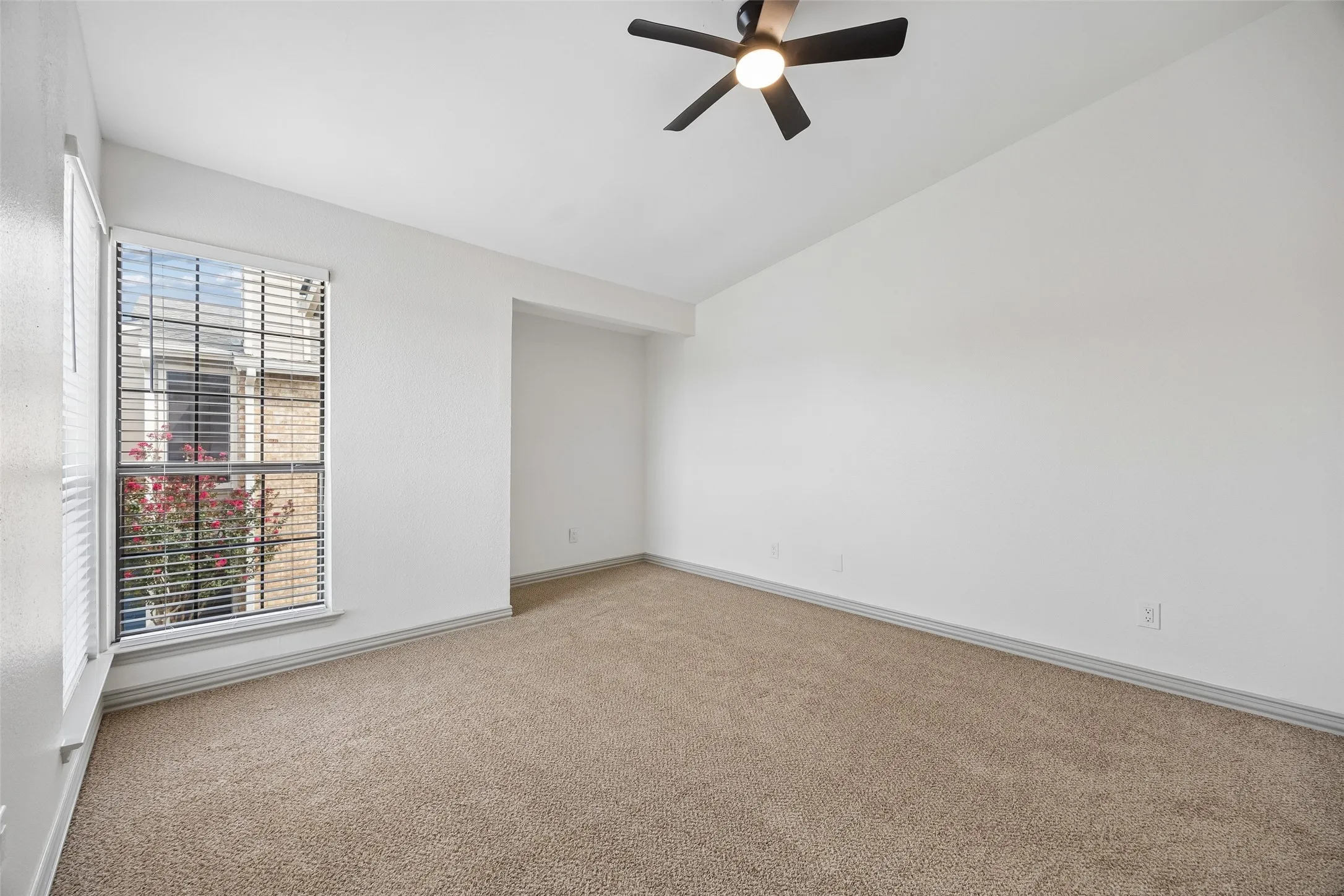 Vaulted ceiling with a ceiling fan, carpeted flooring, and a window with blinds