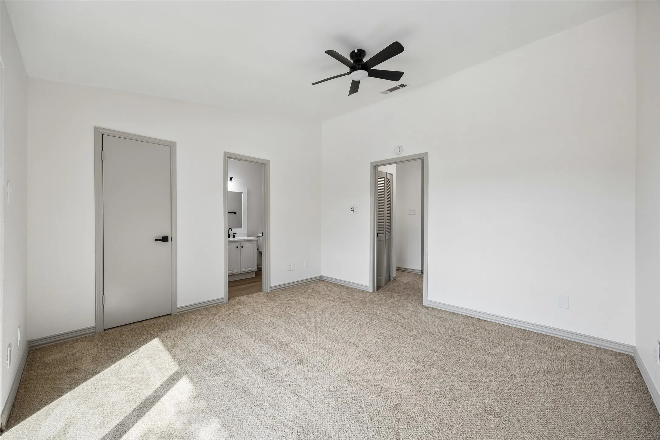 Vaulted ceiling with a black ceiling fan, light-toned carpet flooring, white walls, and gray trim
