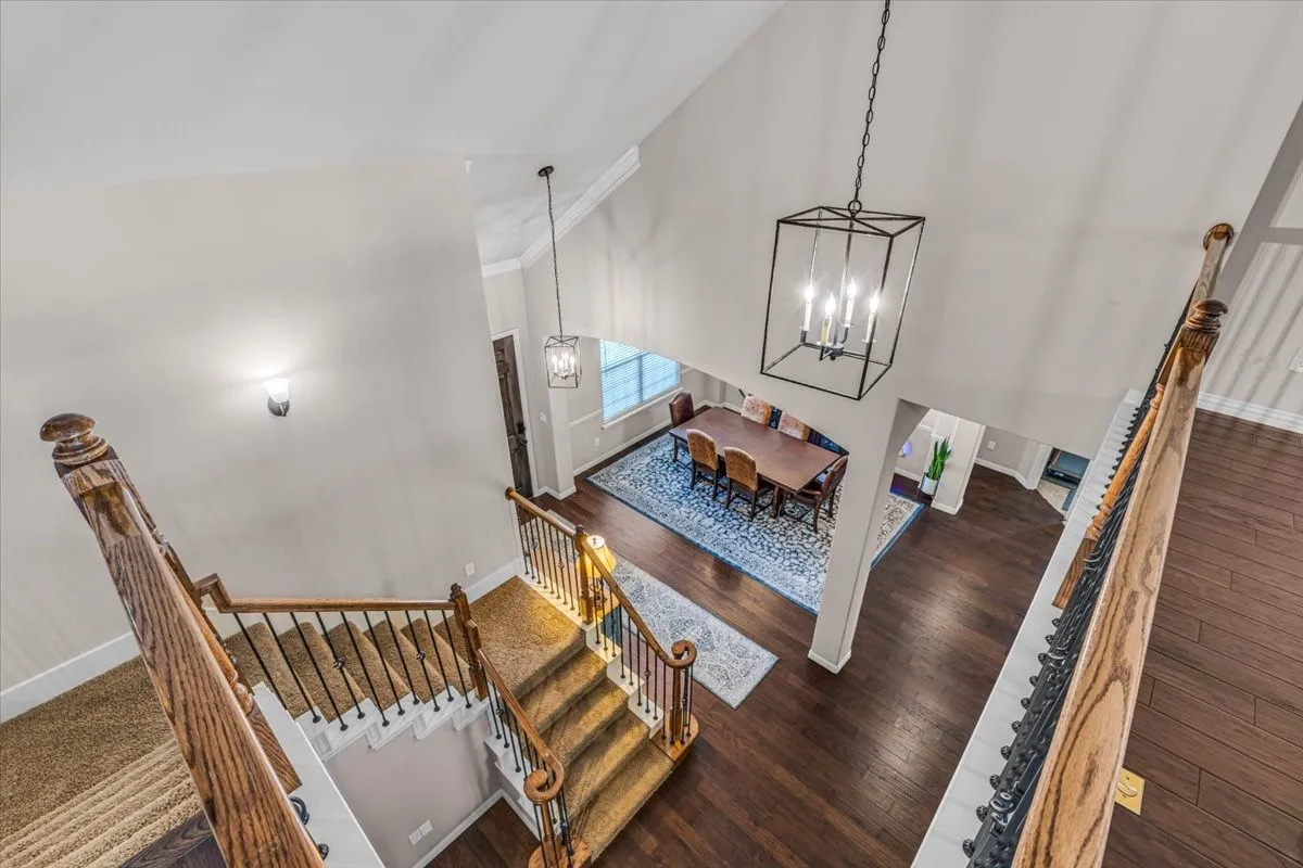 Two-story foyer with high ceilings, dark wood-finish flooring, and a wrought iron staircase railing