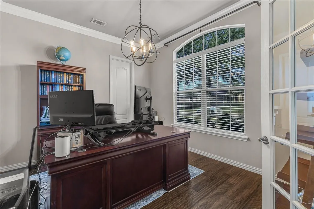 Hardwood-finish flooring, built-in shelving, arched window, French doors, and an overhead spherical chandelier