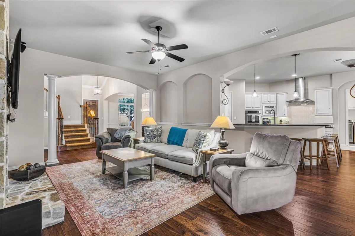 Expansive living area with high ceilings, recessed lighting, and wood-finish flooring