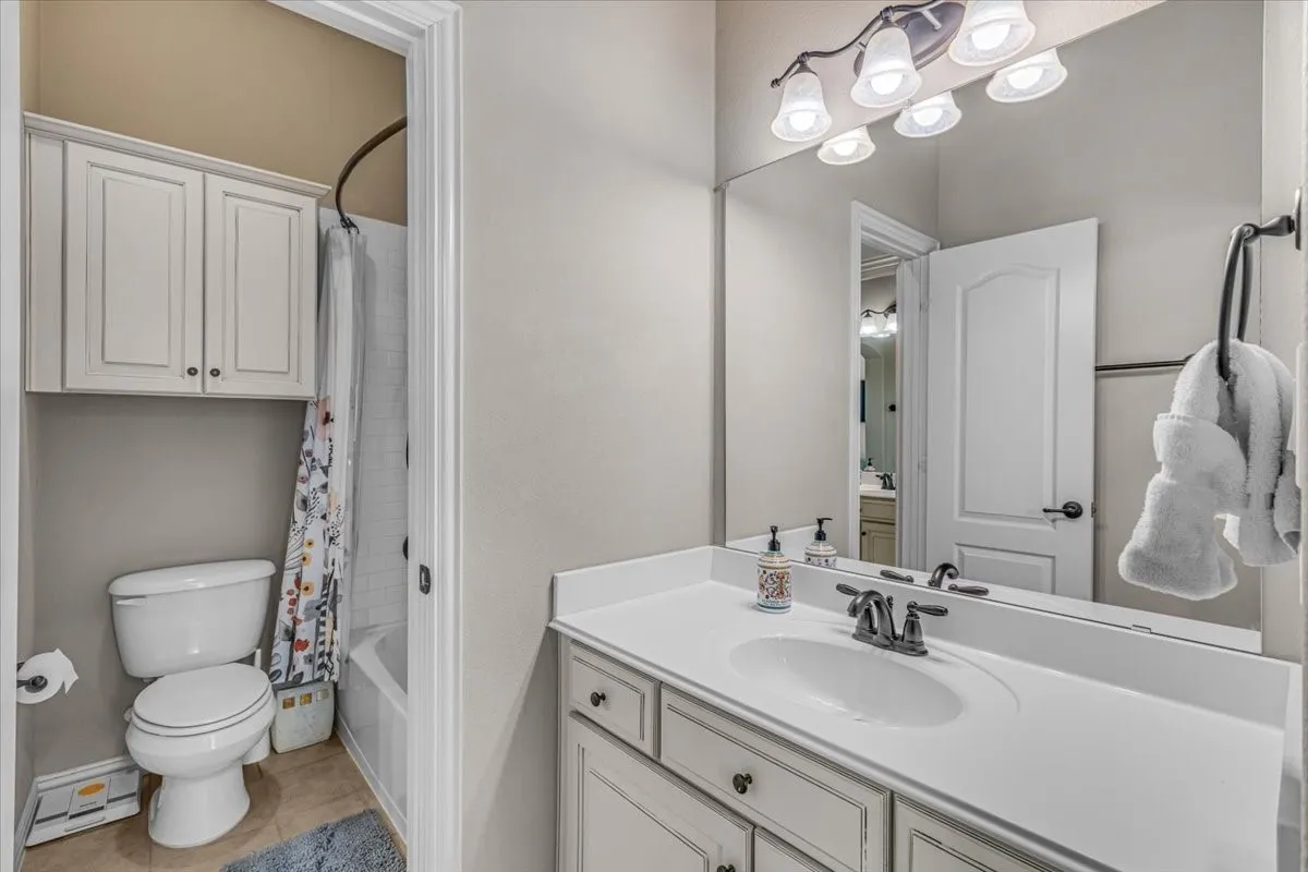 Vanity with a single basin sink and ample counter space, full-width mirror, and a multi-bulb vanity light