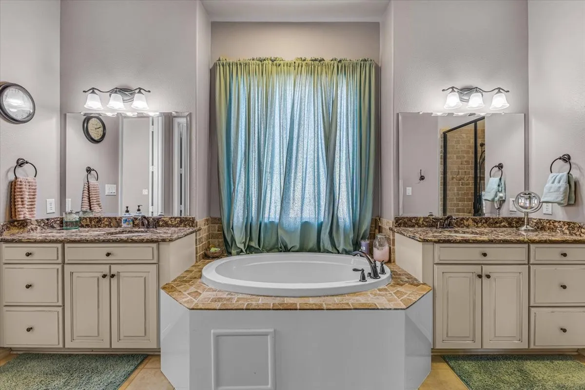 Dual vanity sinks, built-in soaking tub, tiled tub surround, and integrated lighting fixtures