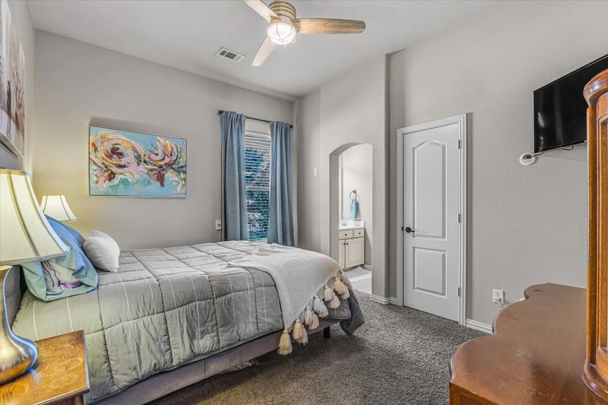 Vaulted ceiling with a ceiling fan, arched doorway, and carpet flooring