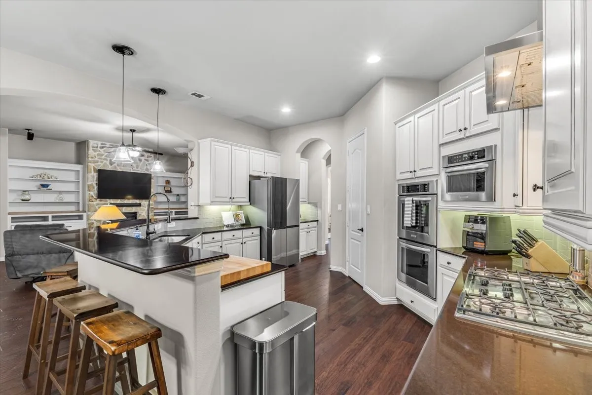 Kitchen featuring white shaker cabinetry, stainless steel appliances, dark countertops, a gas cooktop, and wood-finish flooring