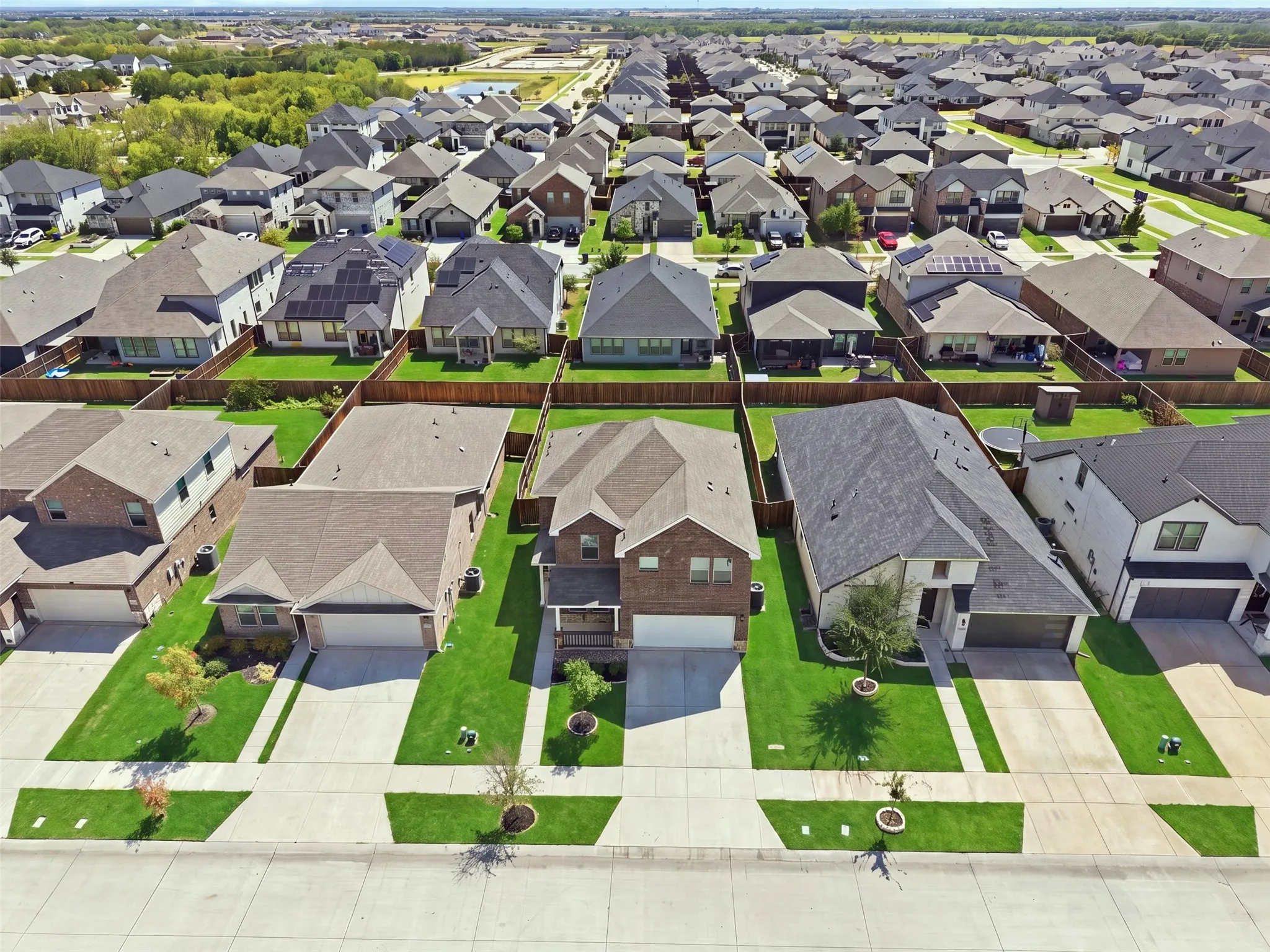 Aerial perspective of a developed residential area featuring multiple single-family homes with pitched roofs and fenced backyards