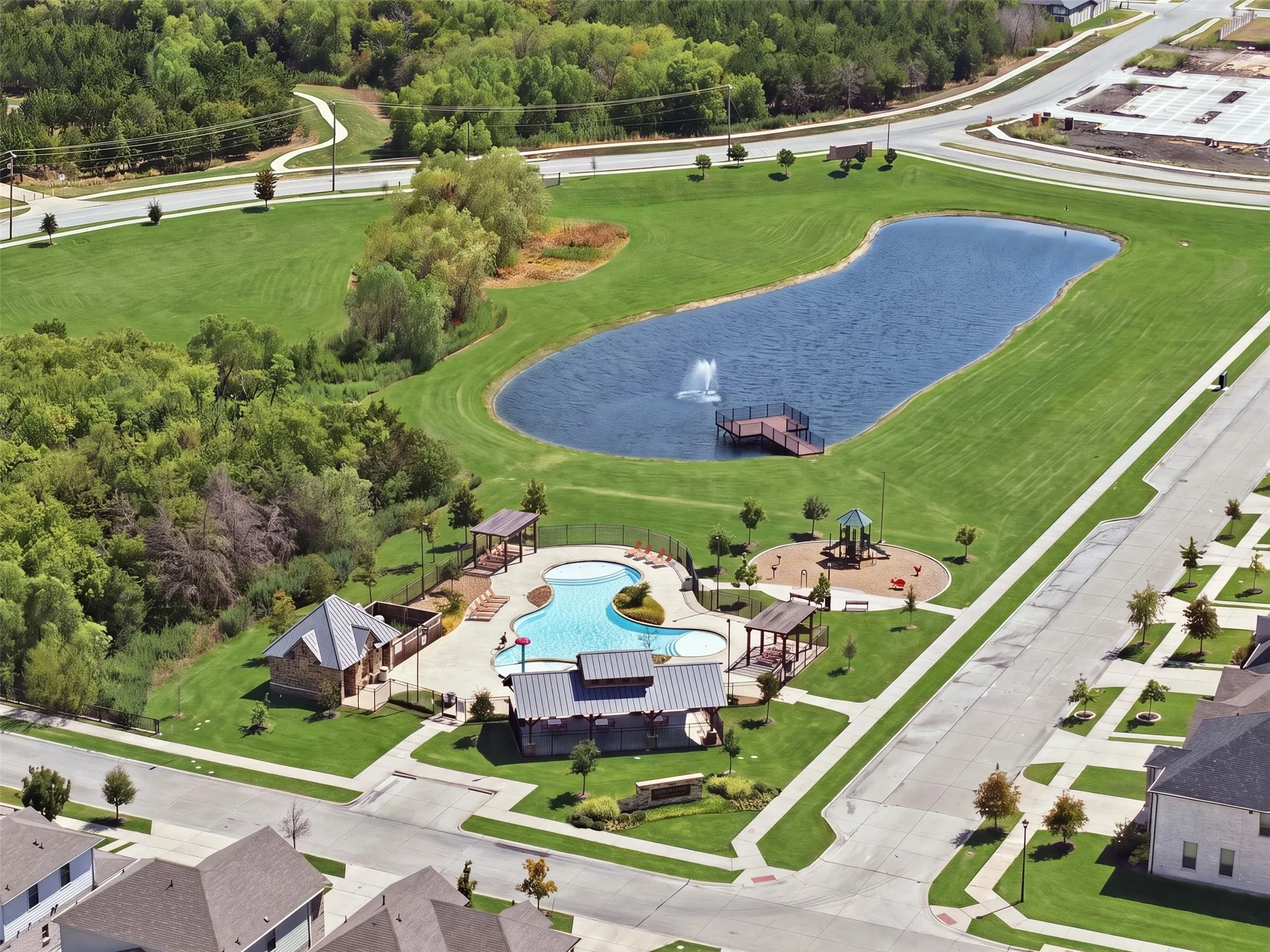 Community amenities featuring a swimming pool, a dedicated pool house, a children's play structure, and a large pond with a water feature and dock