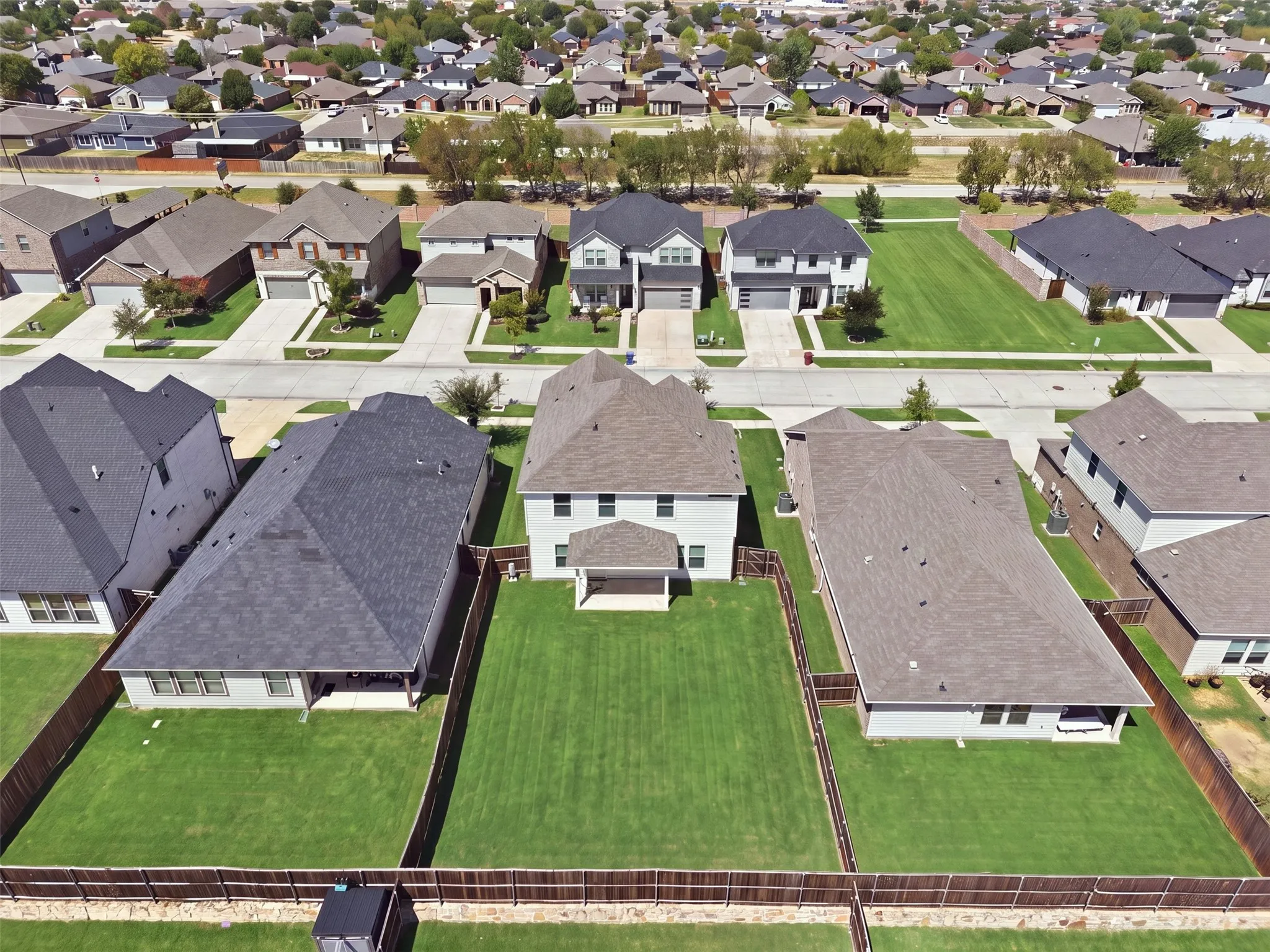 Expansive fenced backyard featuring a manicured lawn