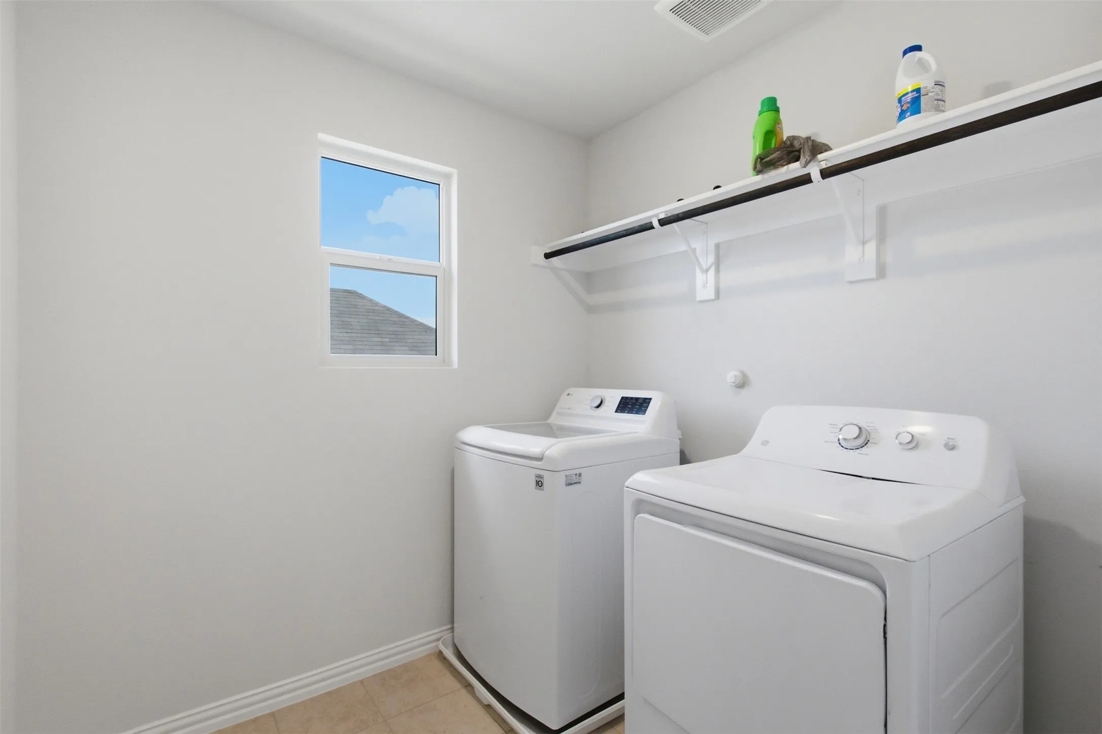 Laundry area upstairs featuring a window, built-in shelving, and light-toned flooring