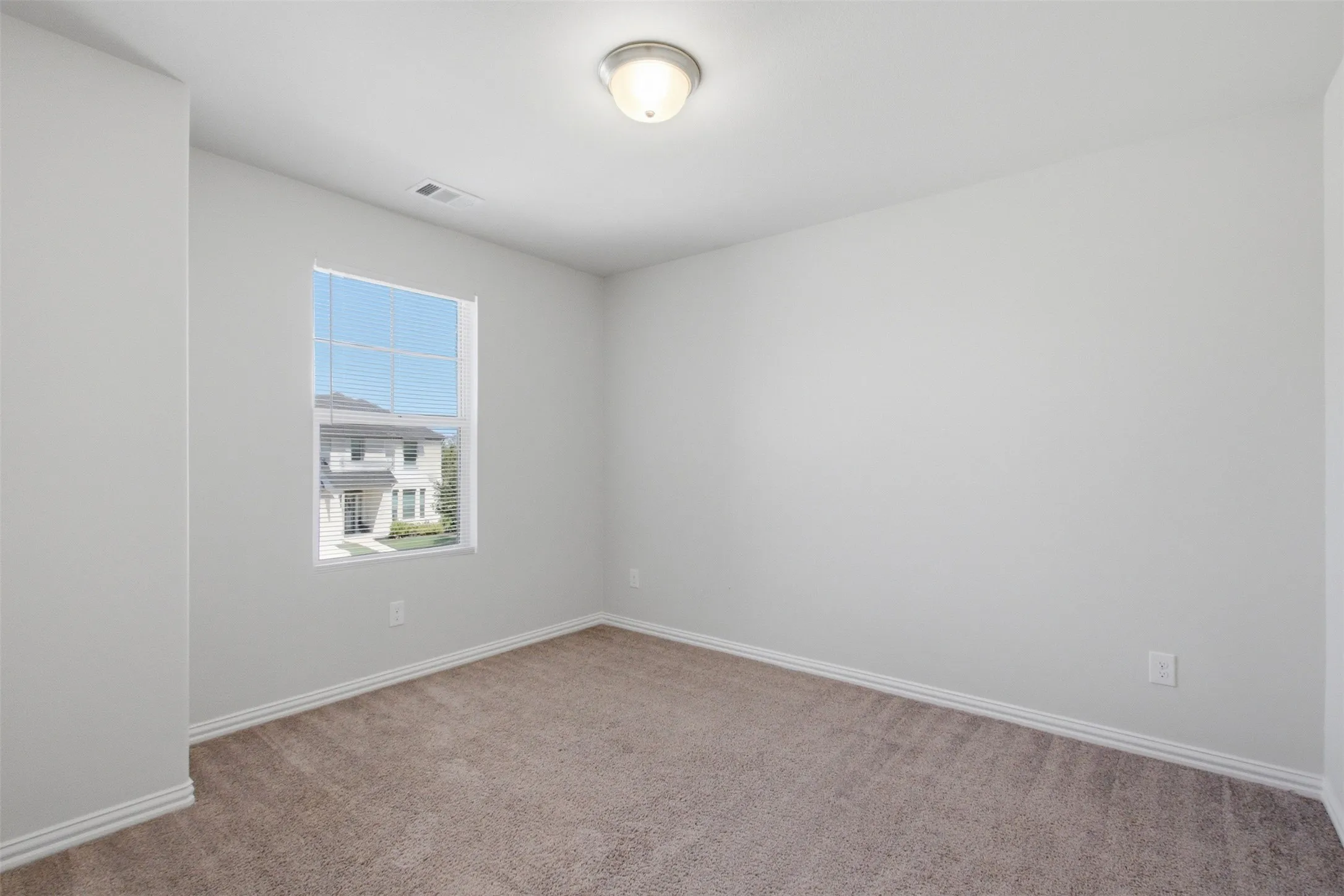 Neutral tone wall paint, flush mount ceiling light fixture, carpeted flooring, and a window with blinds