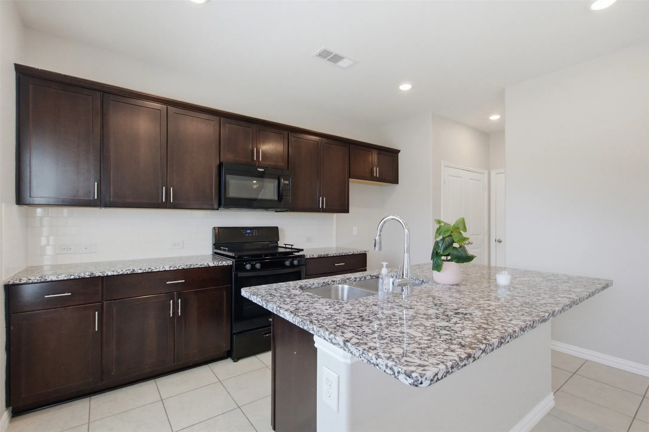 Expansive kitchen island with granite countertop and dual basin sink
