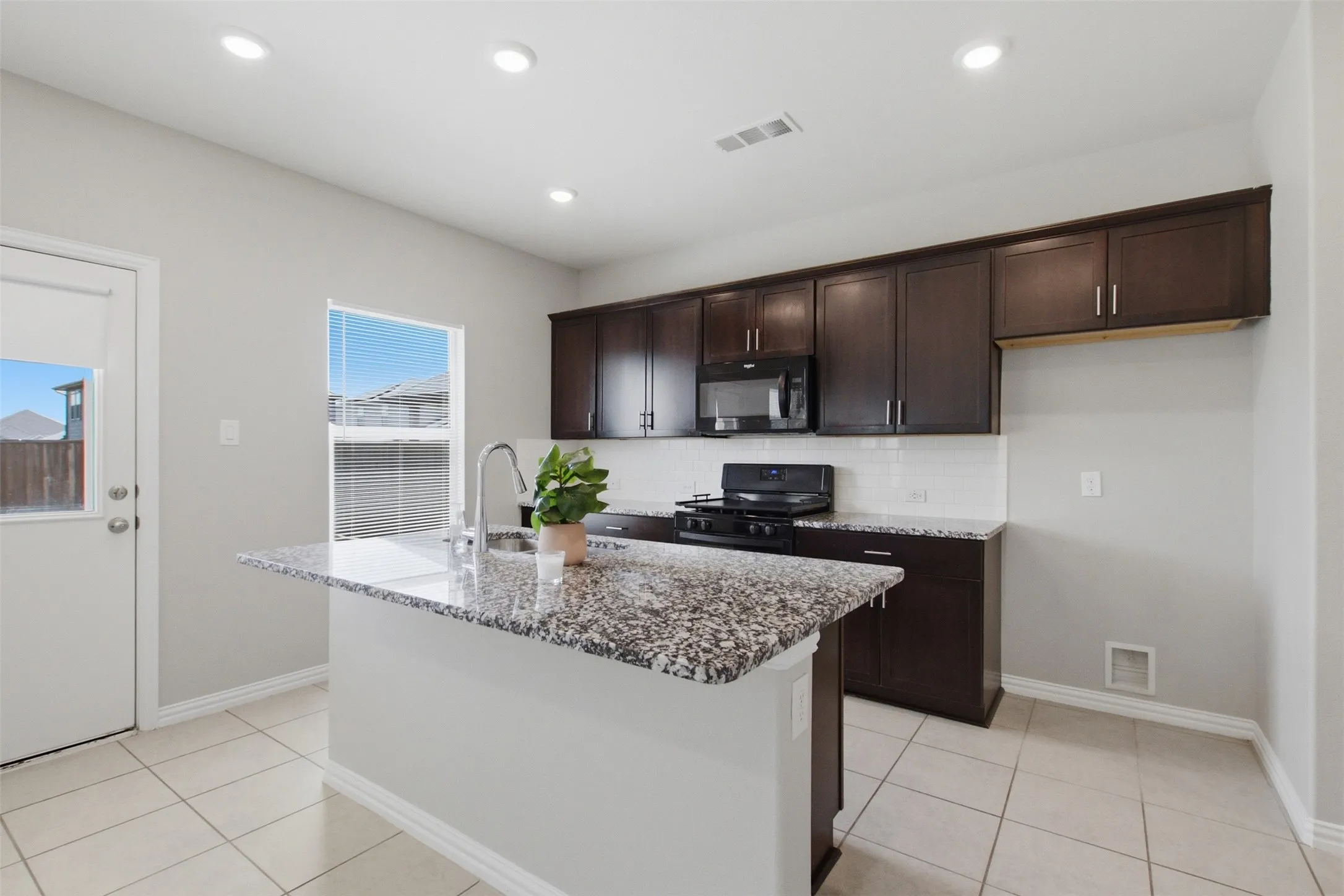 Kitchen featuring a central island with a granite countertop, dark wood-finish cabinetry, tile flooring, and recessed lighting