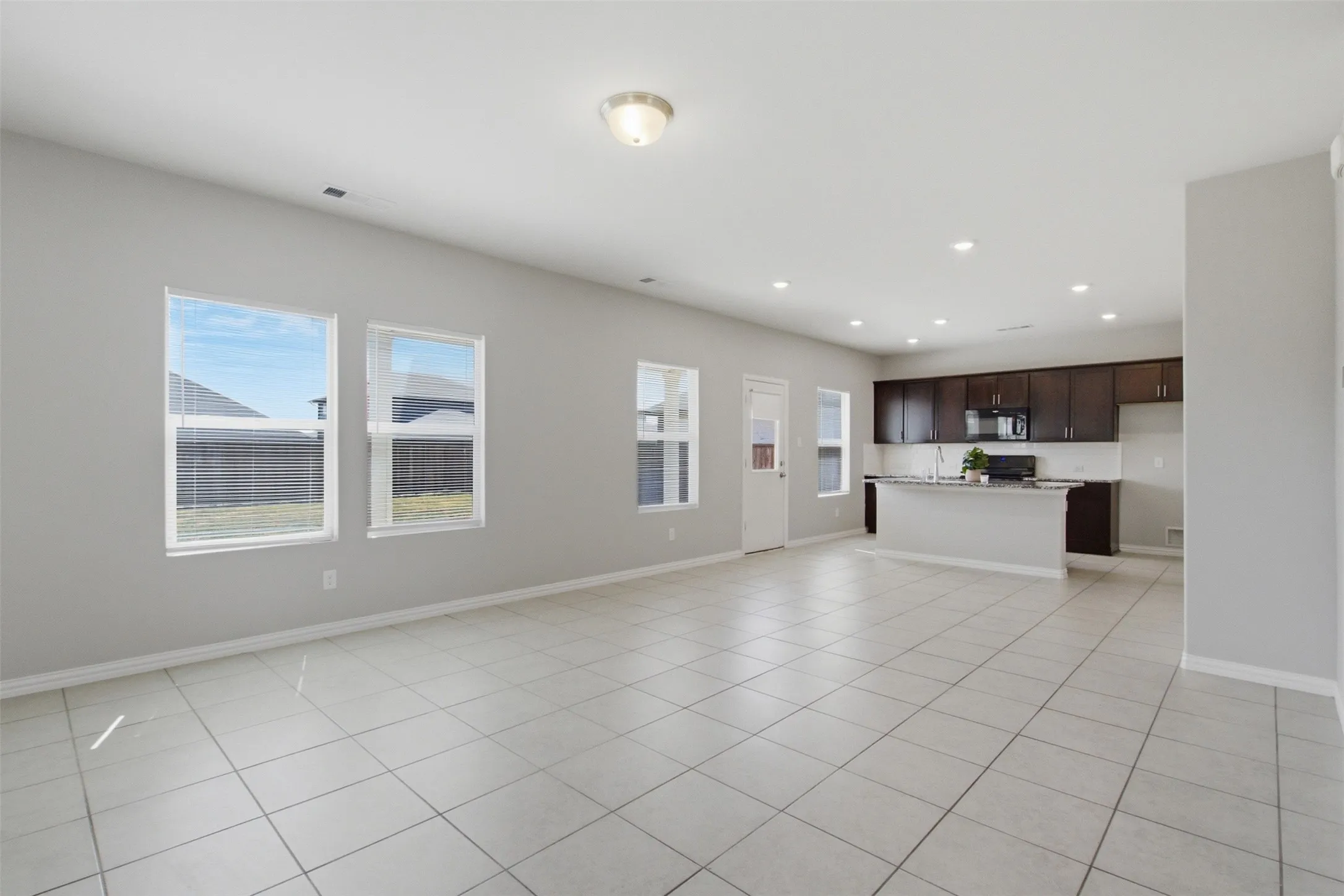 Open-concept living area with tile flooring and multiple windows