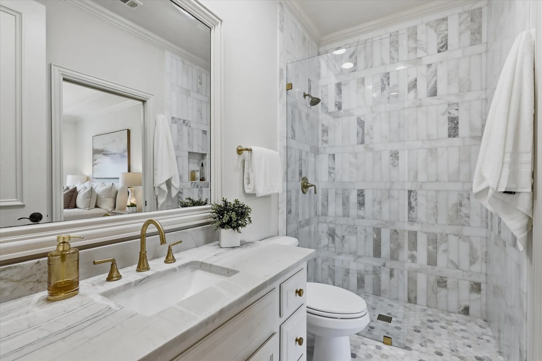 The updated ensuite bath features marble finishes, a glass-enclosed shower and elegant brass fixtures.