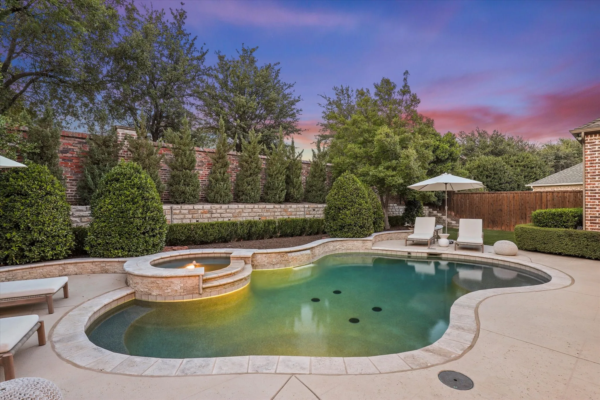 A raised spa, tranquil water feature and multiple lounging areas create a private resort setting.