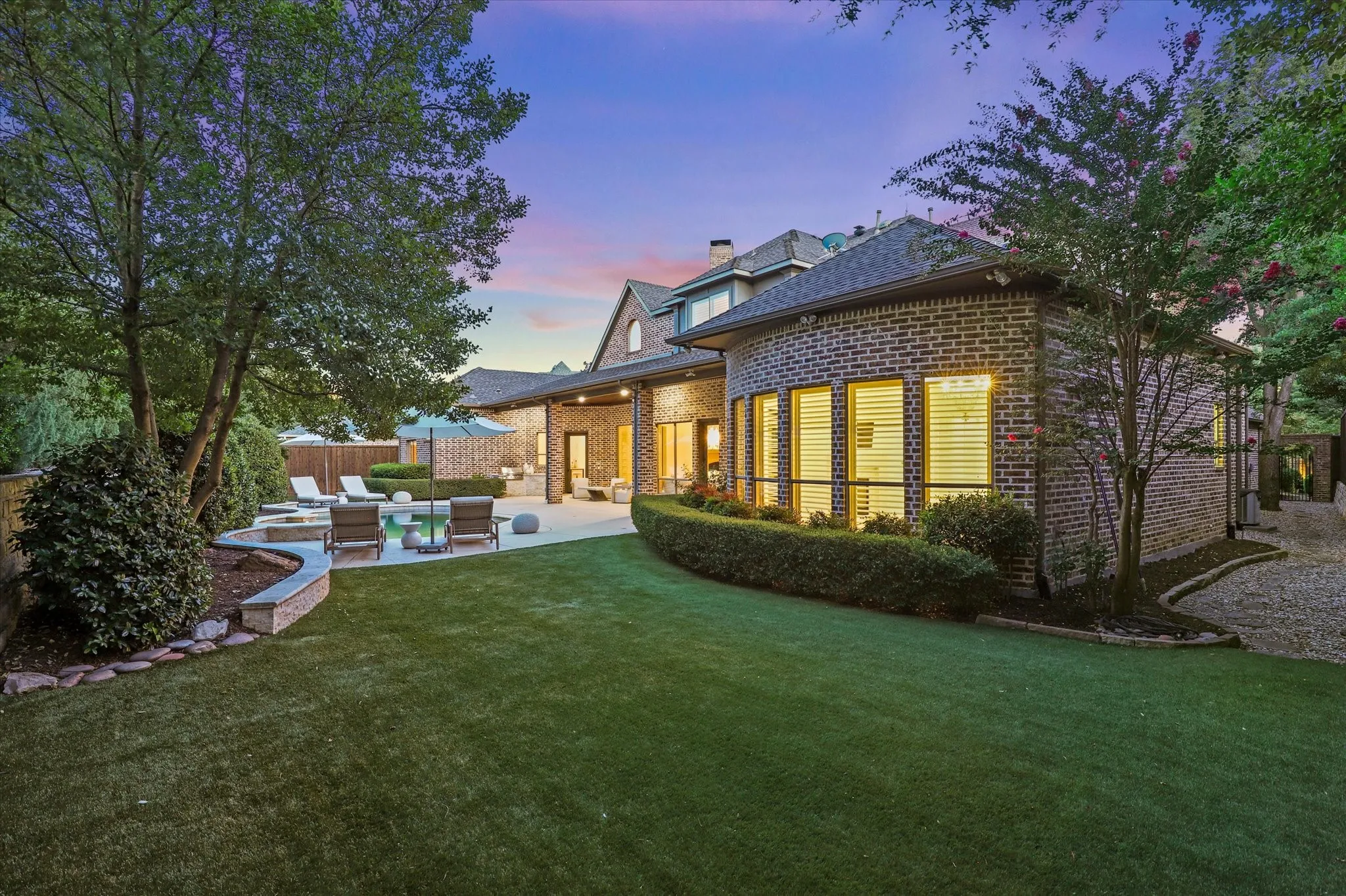 Artificial turf and mature live oaks create a polished, low-maintenance backdrop for outdoor living with plenty of room for play and pets.