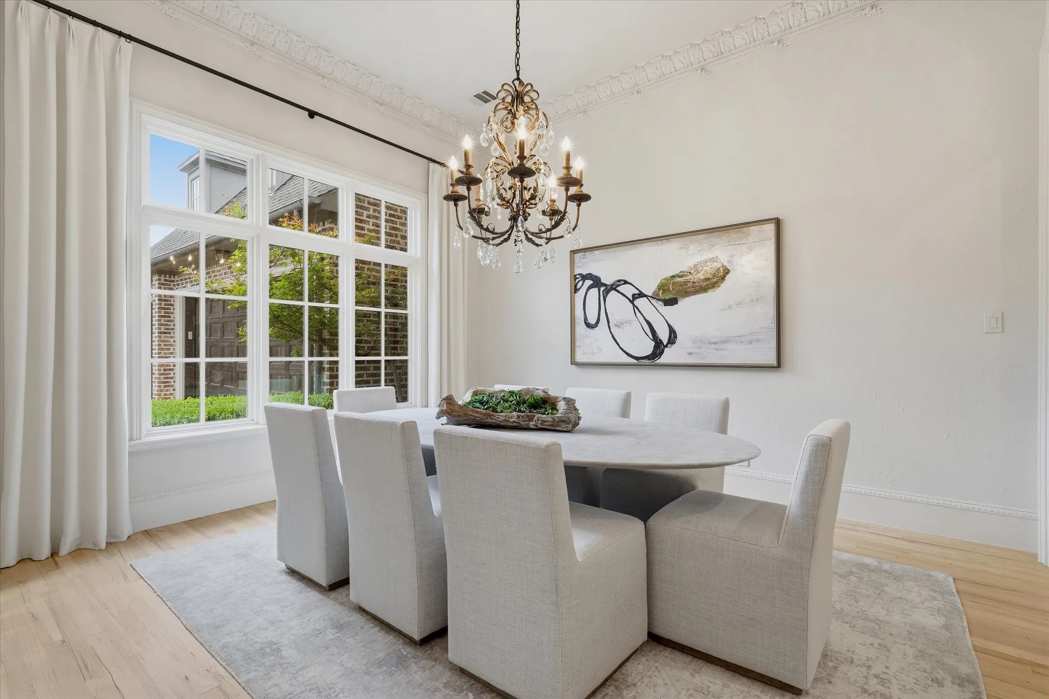 The formal dining room is filled with natural light and detailed with elegant millwork and a statement chandelier.