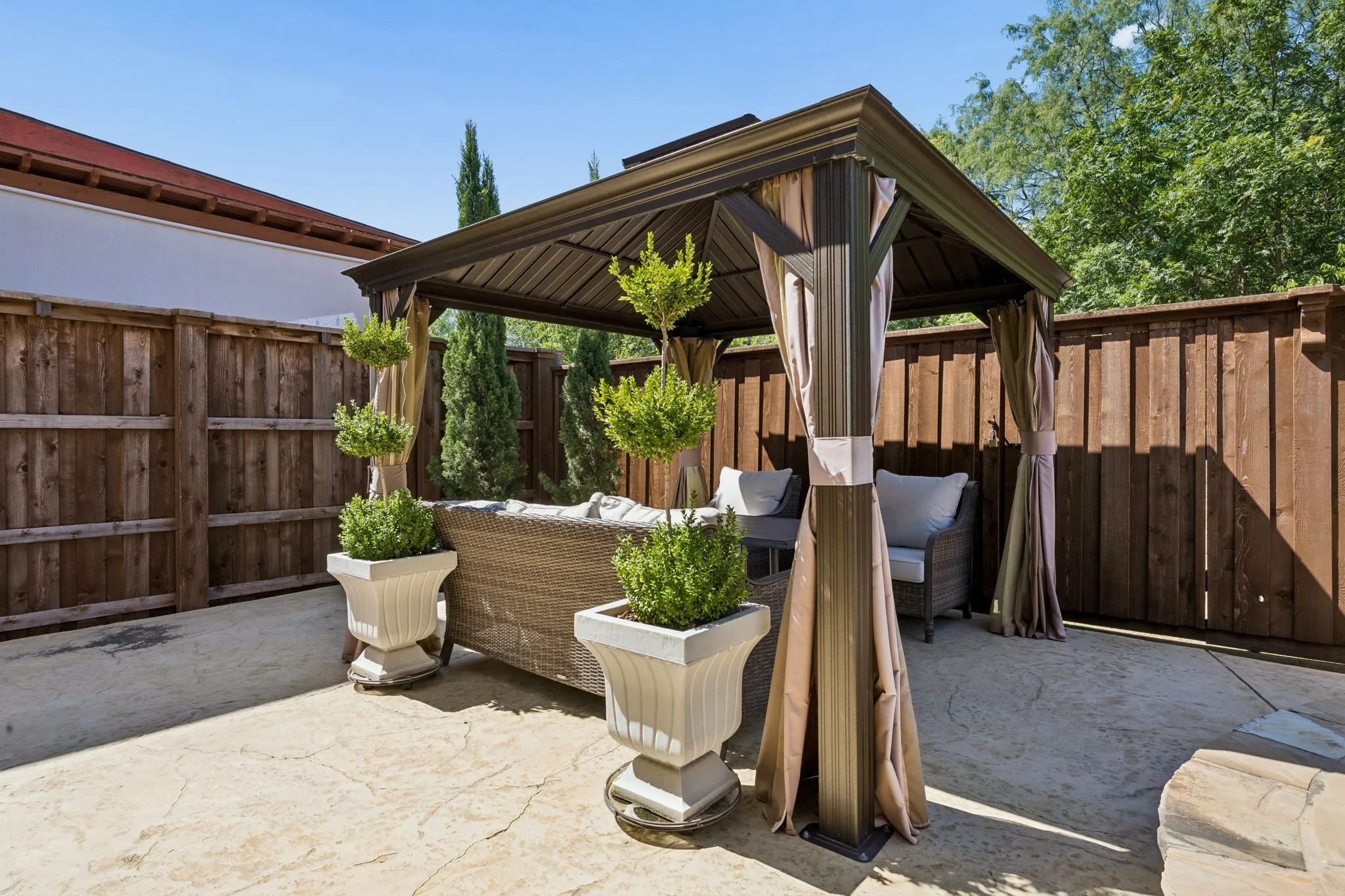 Private cabana creates a shaded outdoor lounge, offering a comfortable spot to gather, unwind and enjoy the backyard setting.