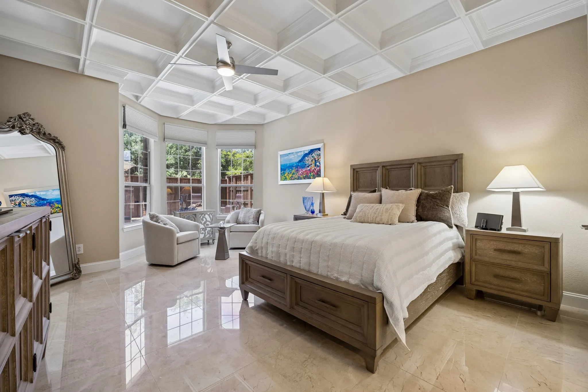 This spacious primary suite is highlighted by a striking coffered ceiling, Bay windows offering picturesque views of the sparkling pool and tranquil backyard. Comfortable sitting area creates a private sanctuary within the room, while the generous layout provides ample space to relax and unwind.